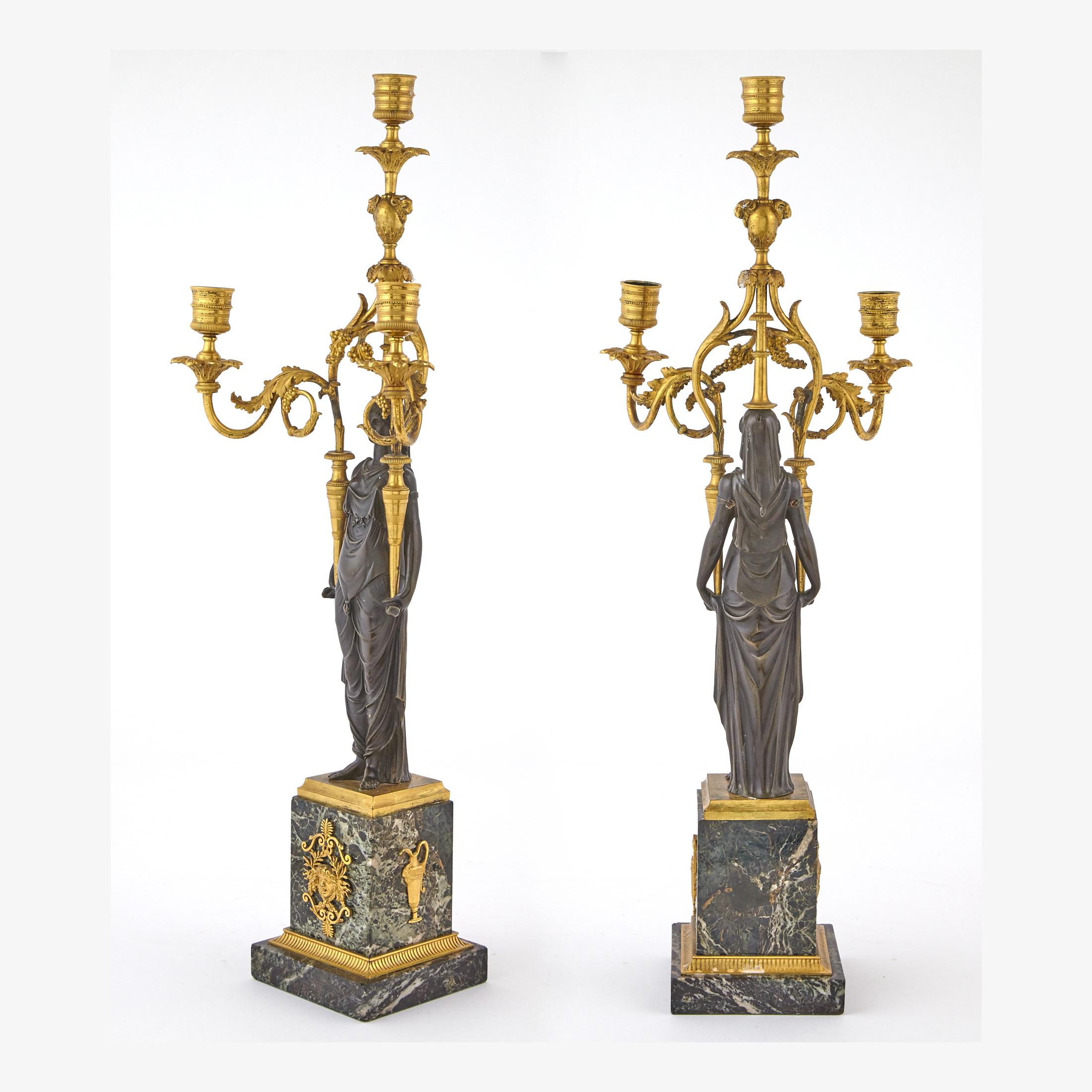 A neoclassical-form woman holding two candle arms with leaves and grapes surmounted on a rectangular base.

Date: 19th century
Origin: French
Dimension: 24 1/2 in. x 9 in.
