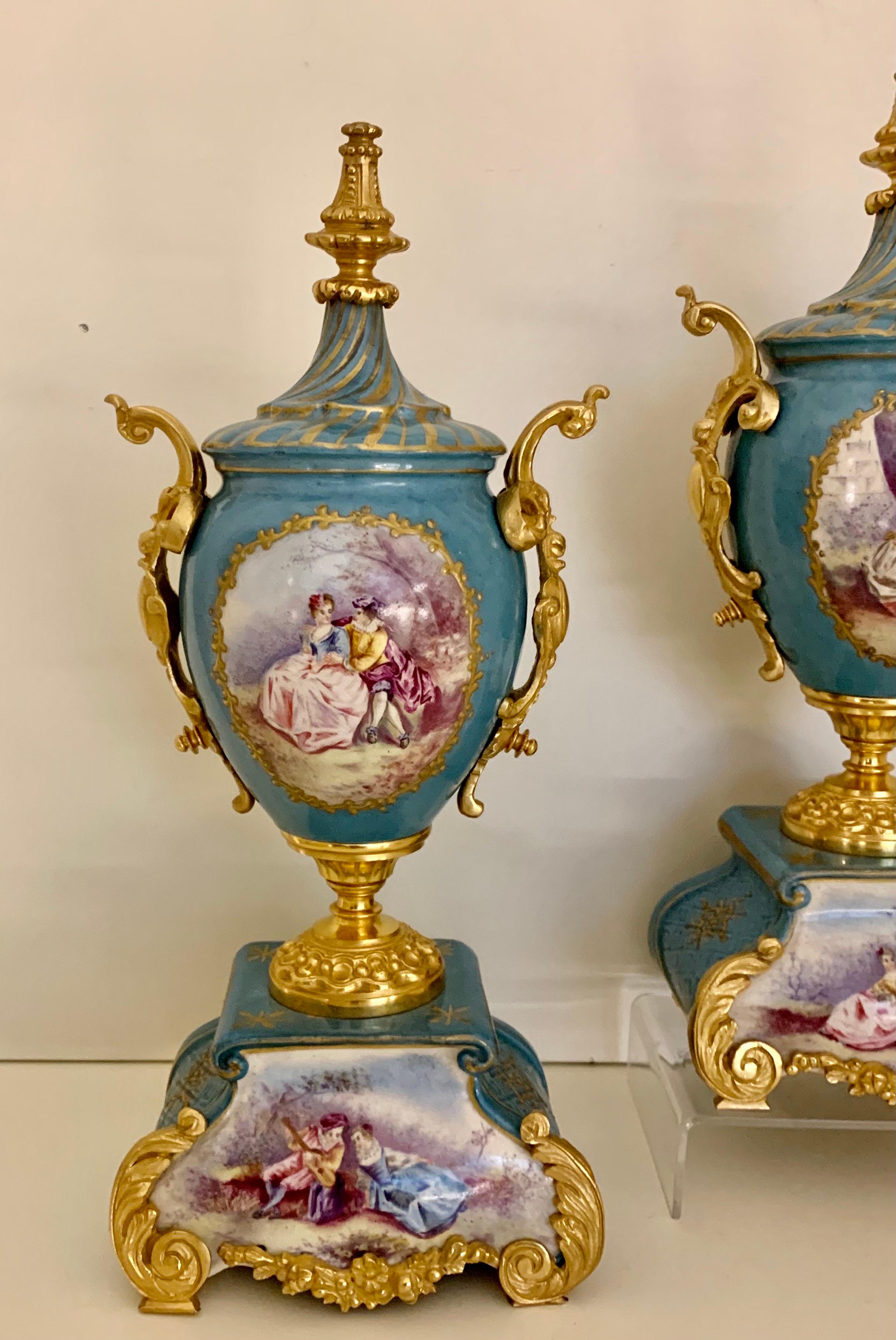 A pair of sevres style porcelain and gilt bronze mounted vases of baluster form, having gilt Rococo decoration throughout, Hand painted with a scene of 2 lovers in a garden. These are unusual because they have another painted scene to the bases or