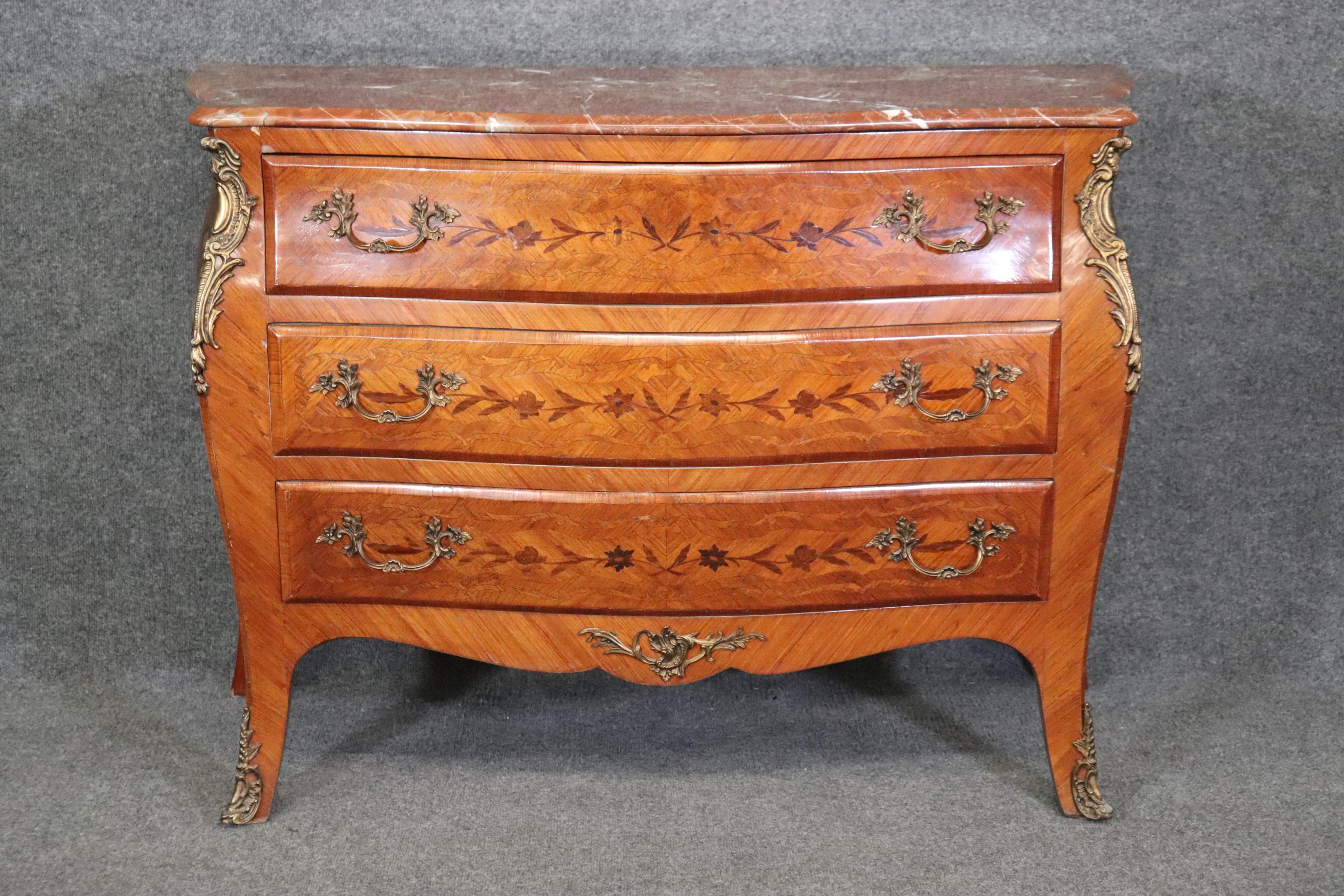 This is a beautiful marble top commode in the Louis XV style with a beautiful marble top and gorgeous wood quality. The piece features beautiful inlay and harmonious coloration between the woods and the marble. The piece is in good condition and