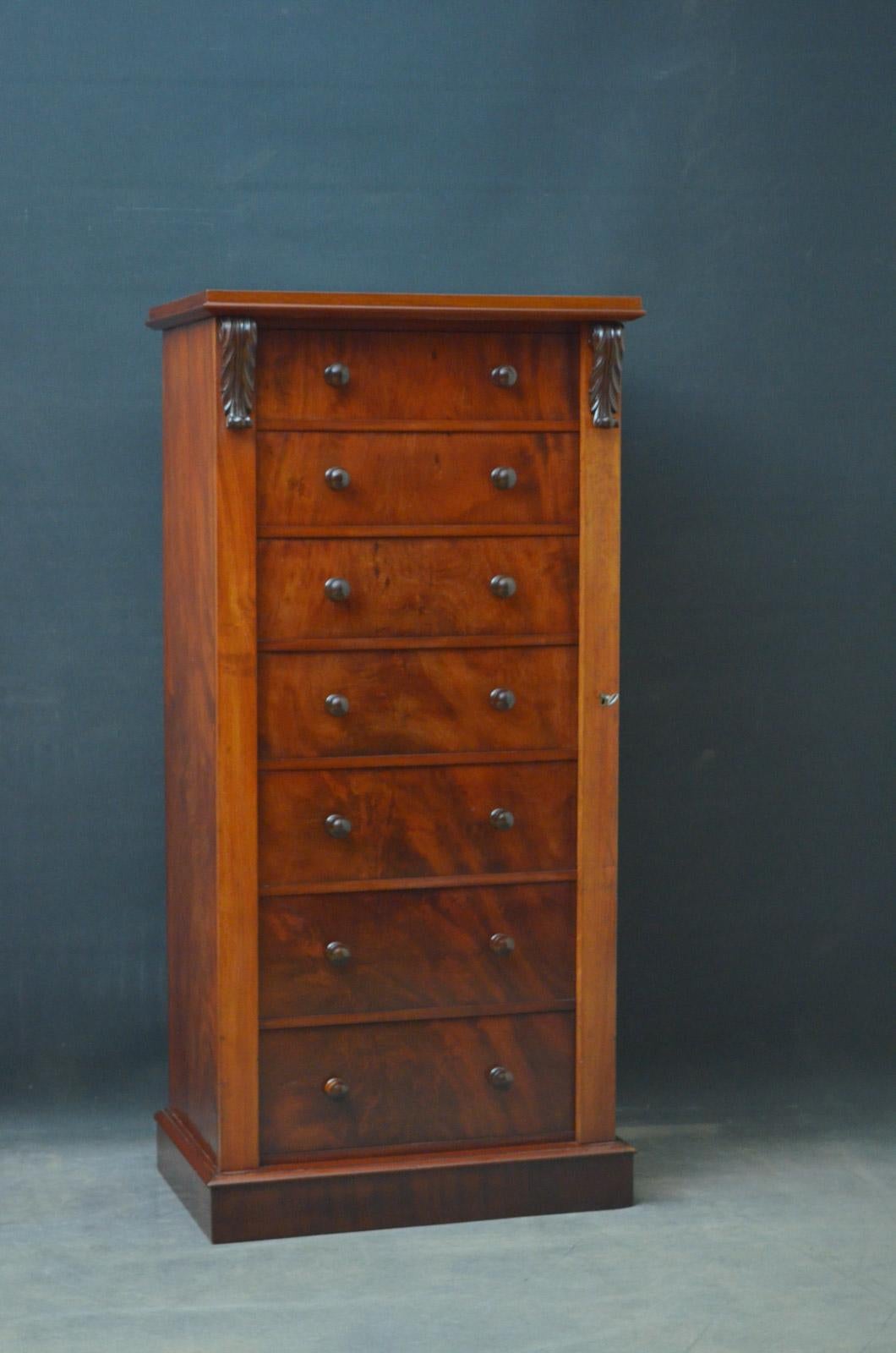 Sn4065, fine quality Victorian mahogany Wellington chest of drawers, having molded top above seven graduated, mahogany lined drawers all fitted with original turned handles and flanked by locking bar with original working lock and drop carvings,