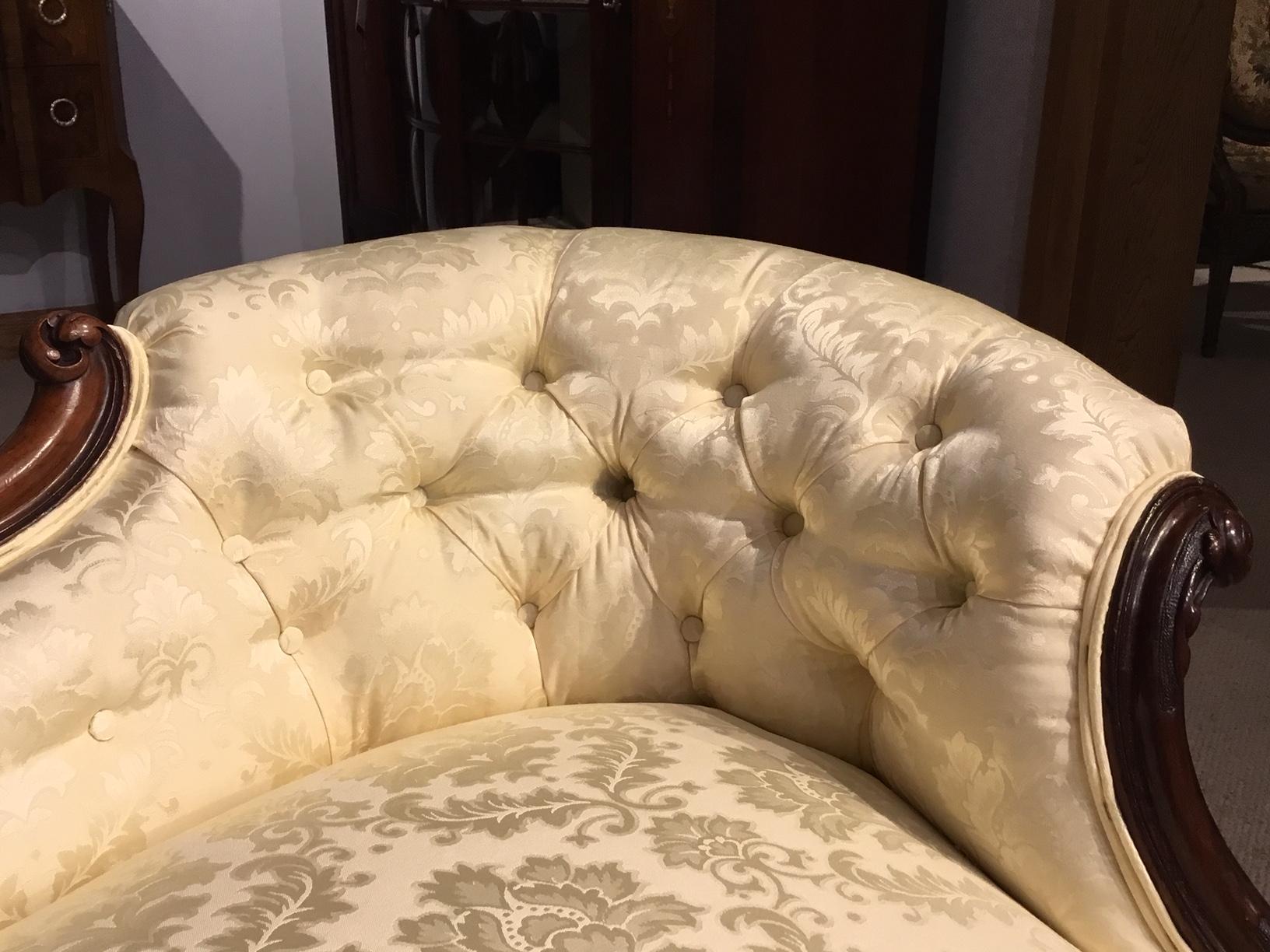 A fine quality walnut Victorian Period boudoir sofa. Having a shaped back with a central carved walnut show frame, deep buttoned curved ends and a sprung seat. The rolled arms having finely carved floral detail which is repeated on the curved seat