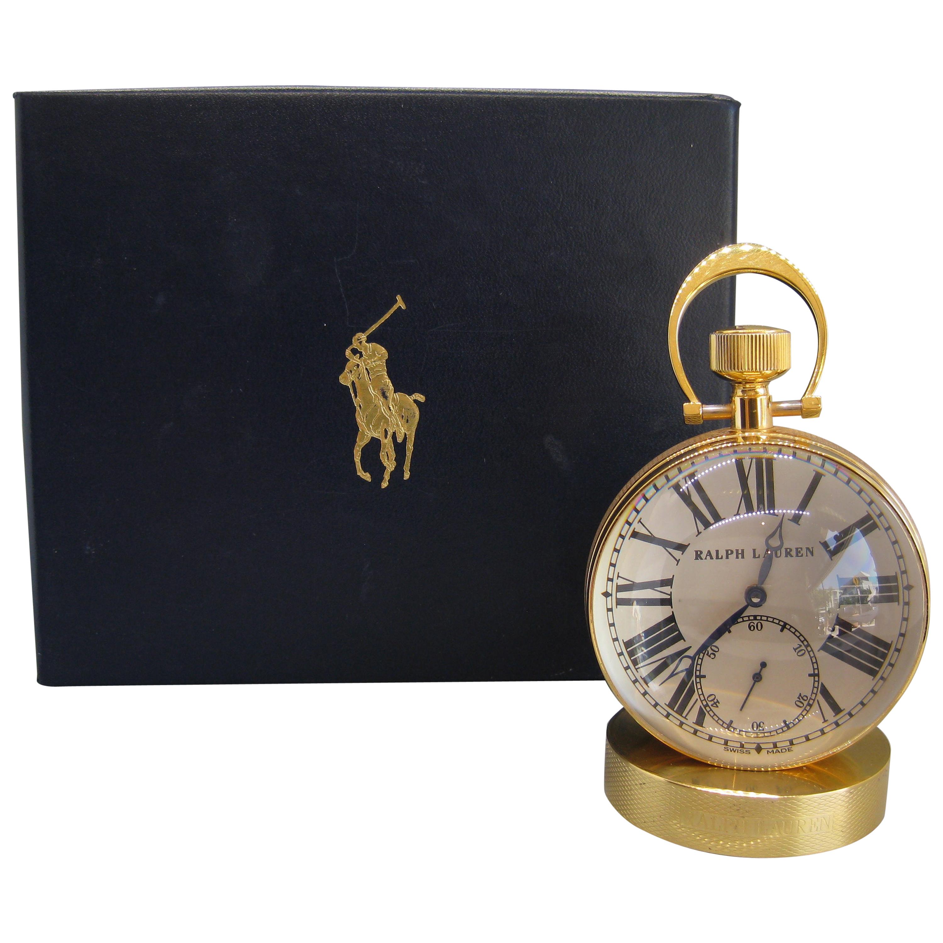 Fine Ralph Lauren brass and glass ball shaped desk clock. The clock works and keeps accurate time. Has Swiss 17 jewel works. Comes with the original box. Great design and form. Comes with the solid brass base to hold the clock. In excellent shape