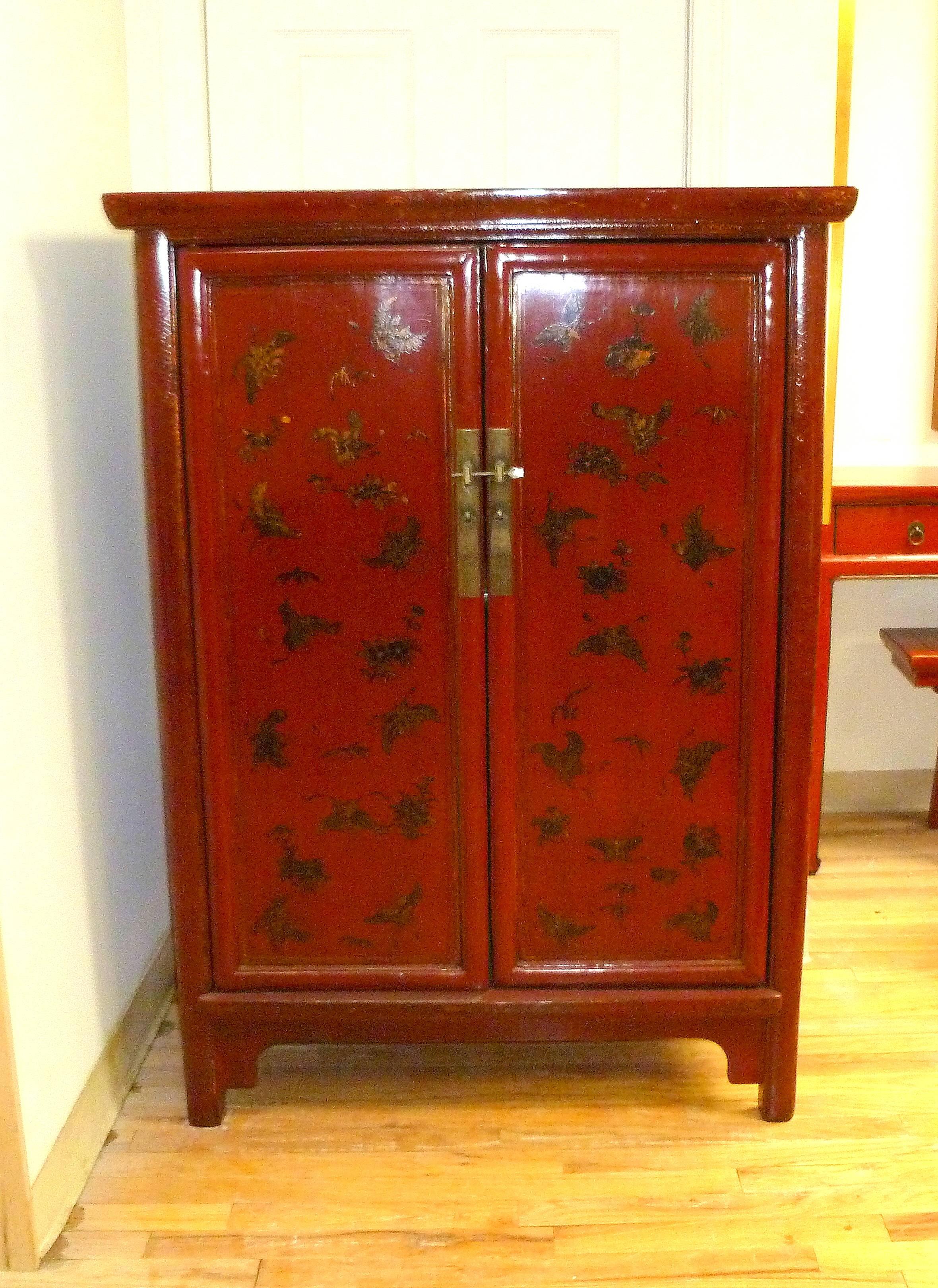Fine red lacquer cabinet with hand painted gold gilt butterfly motif with pair of doors and shelf inside