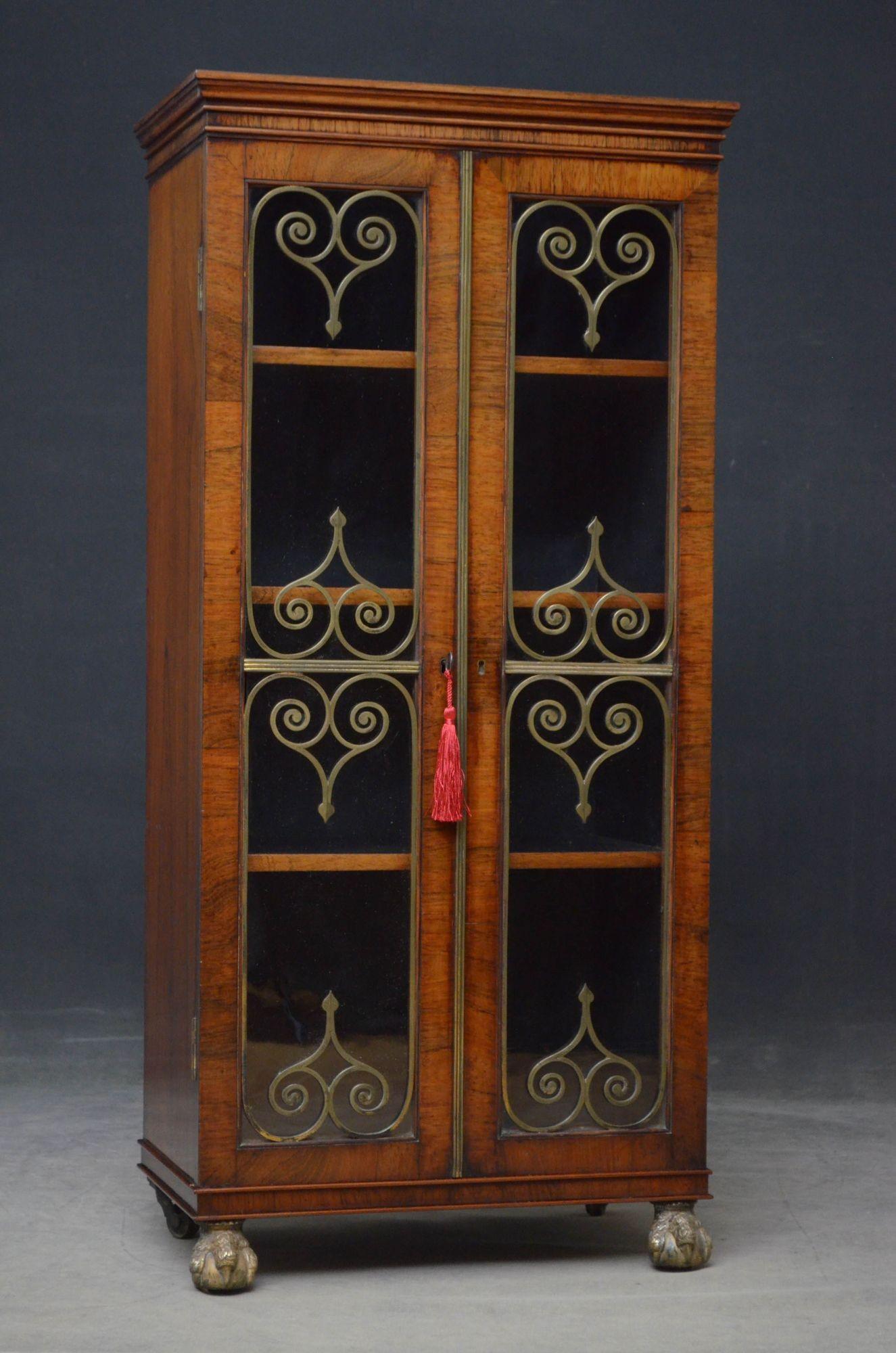 Sn5434 Fine and elegant Regency rosewood bookcase of narrow proportions, having oversailing top above shallow frieze and a pair of glazed doors fitted with original working lock and key, decorated with scroll brasses and reeded brass central bead