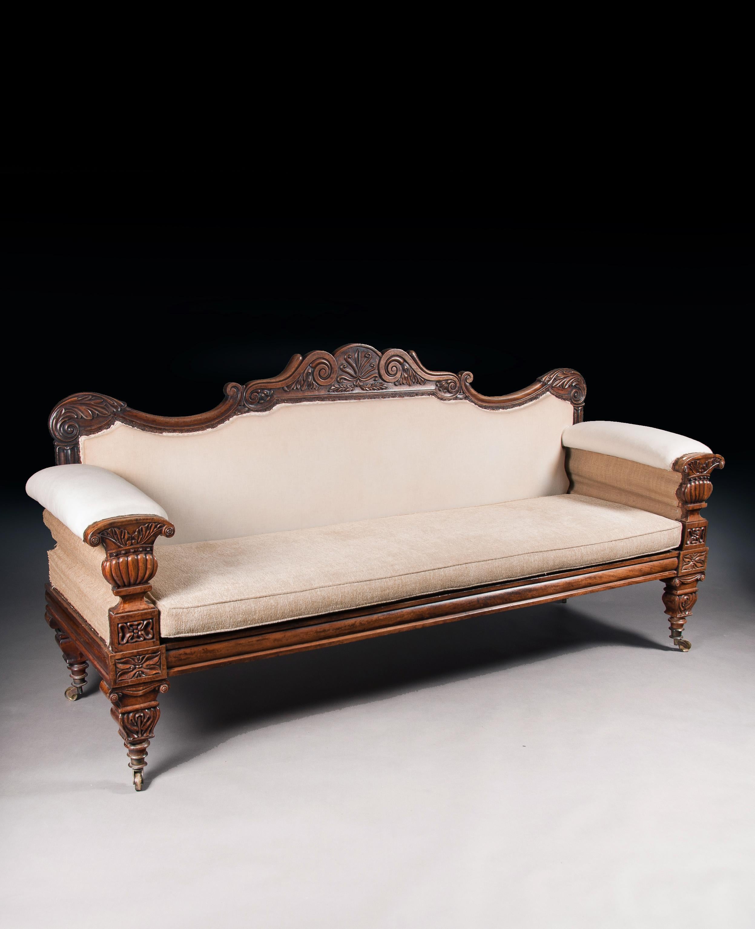 A very fine English Regency carved mahogany sofa after a design by John Taylor incorporating Greek and Roman elements.

English, circa 1825.

Having acanthus leaf wrapped carved scroll ends, the top rail features a shaped foliate double scroll