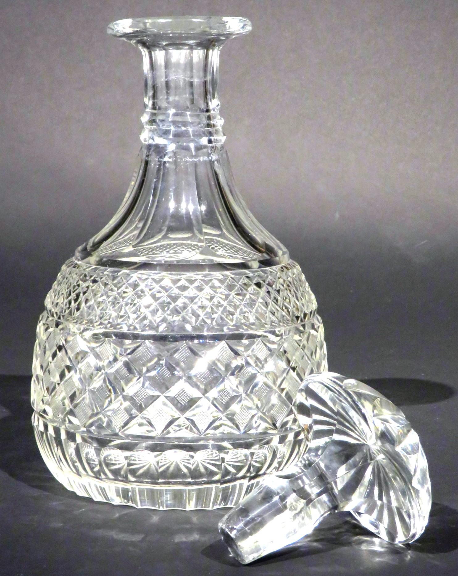 The greyish glass body showing a mitre-cut double ringed neck over broad flutes rising to its original mushroom stopper, the shoulders banded with diamond cut motifs & mitre-cut rings over a band of cross-cut hobnail motifs, the base with a running