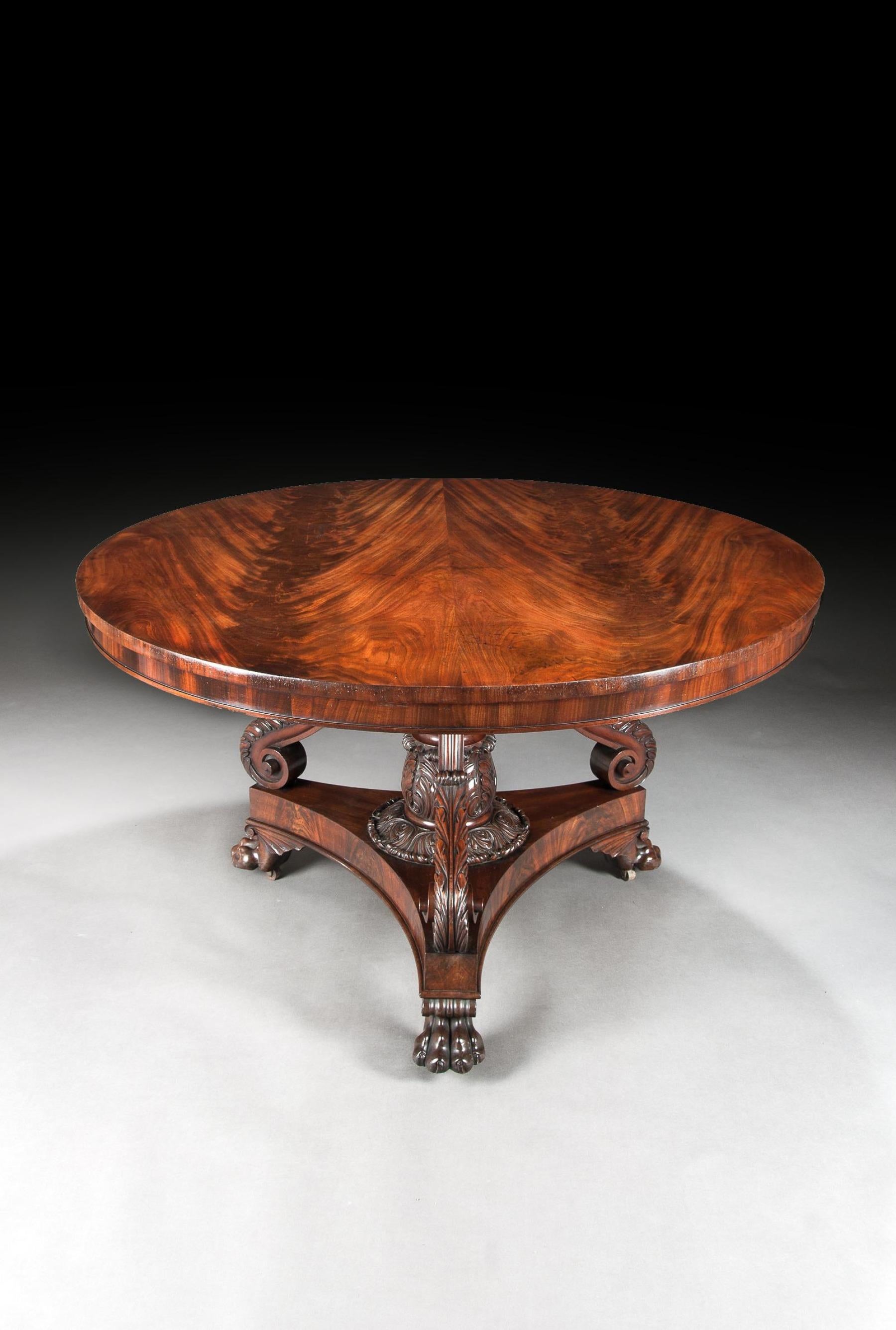A superb 19th century Regency period mahogany centre table on a finely carved rare and unusual base.

English, circa 1825.

The circular flame mahogany book-match veneered tilt-top, raised upon a turned column with finely carved acanthus leaf