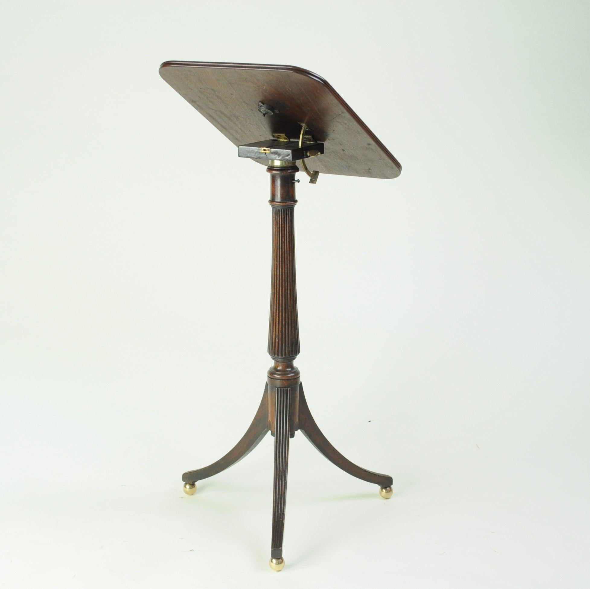 A fine quality Regency period mahogany Lectern or reading table with adjustable tilt top supported on a turned and reeded vase shaped column on a swept tripod base with original brass ball feet.
When not being used as a lectern the top folds flat