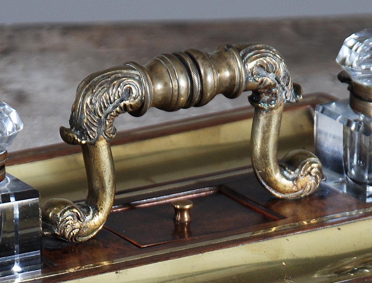 Ein hochwertiges Schreibtischset aus Palisanderholz mit Messingbeschlägen. Die verschnörkelten Messinggriffe mit Akanthusmotiv werden von Kristalltintenfässern flankiert, die in flachen Vertiefungen sitzen. Auf beiden Seiten befinden sich