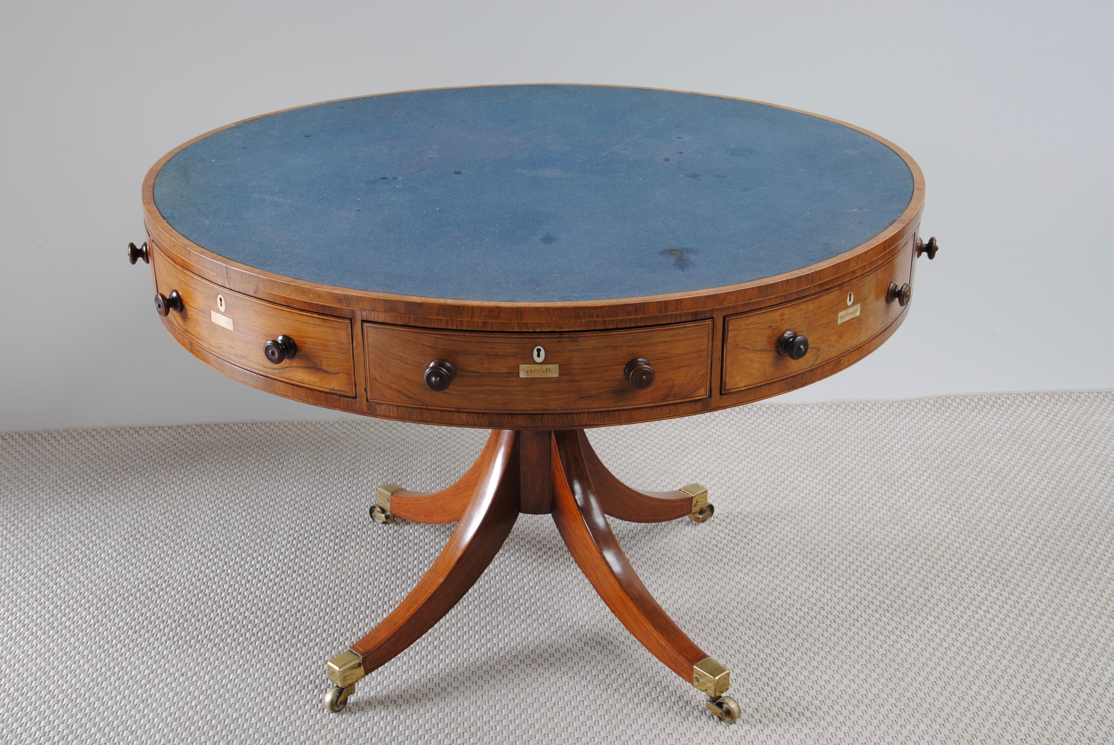 A Regency rosewood drum table with cross bandings and boxwood lines. The two larger drawers fitted with the Gillow design alphabet as found on the architects table. The top with blue baize.
      
