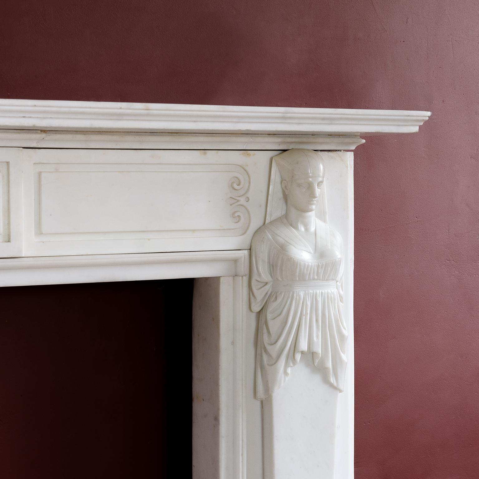 A fine Regency period Statuary marble fireplace in the Egyptian manner, the moulded shelf above frieze with incised channel-moulded decoration and central plaque, the caryatid jambs depicting Egyptian Goddess Isis, raised on footblocks. Fine quality