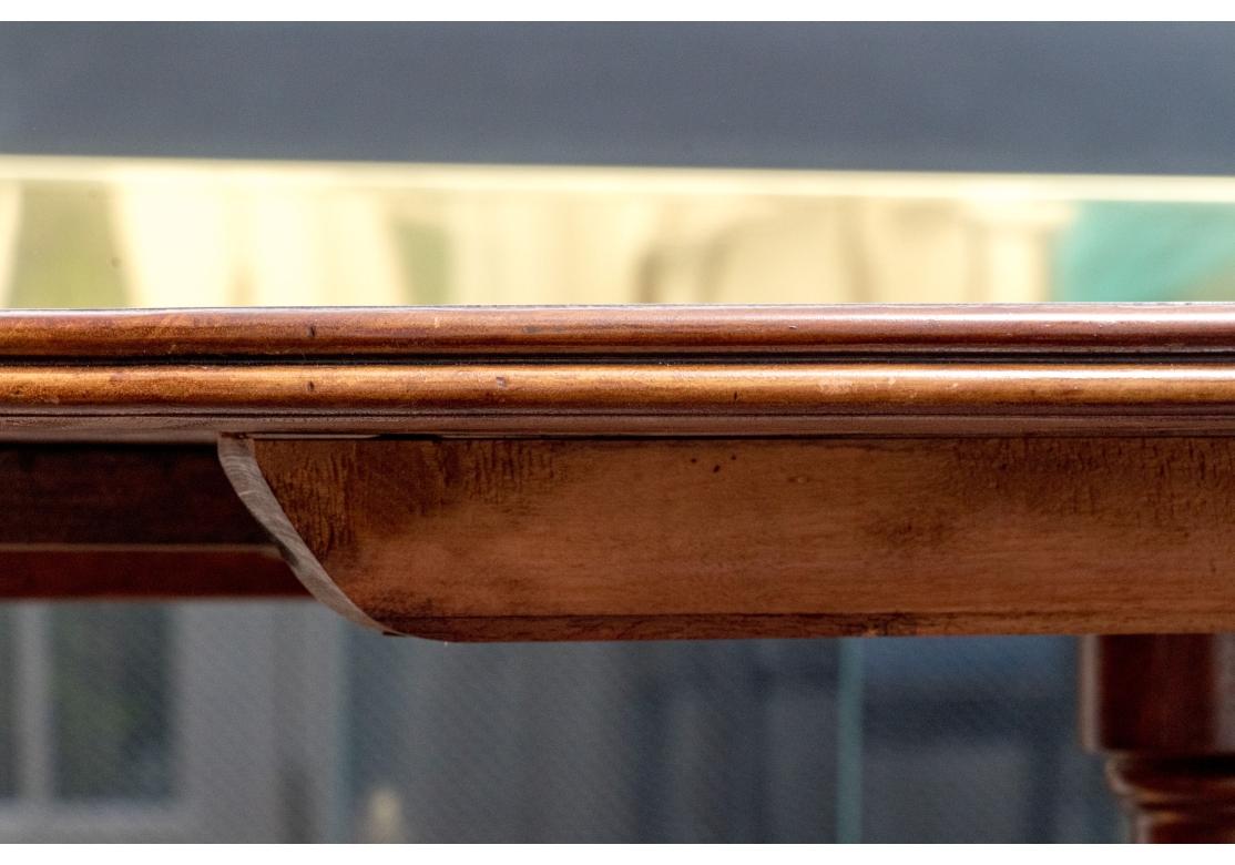 La table ovale en acajou avec incrustation de lignes en bois foncé, avec un grain de bois particulièrement fin et une couleur exceptionnelle. Pieds de piédestal classiques en roseau avec un pied de patte en laiton bien défini et complexe. La table a