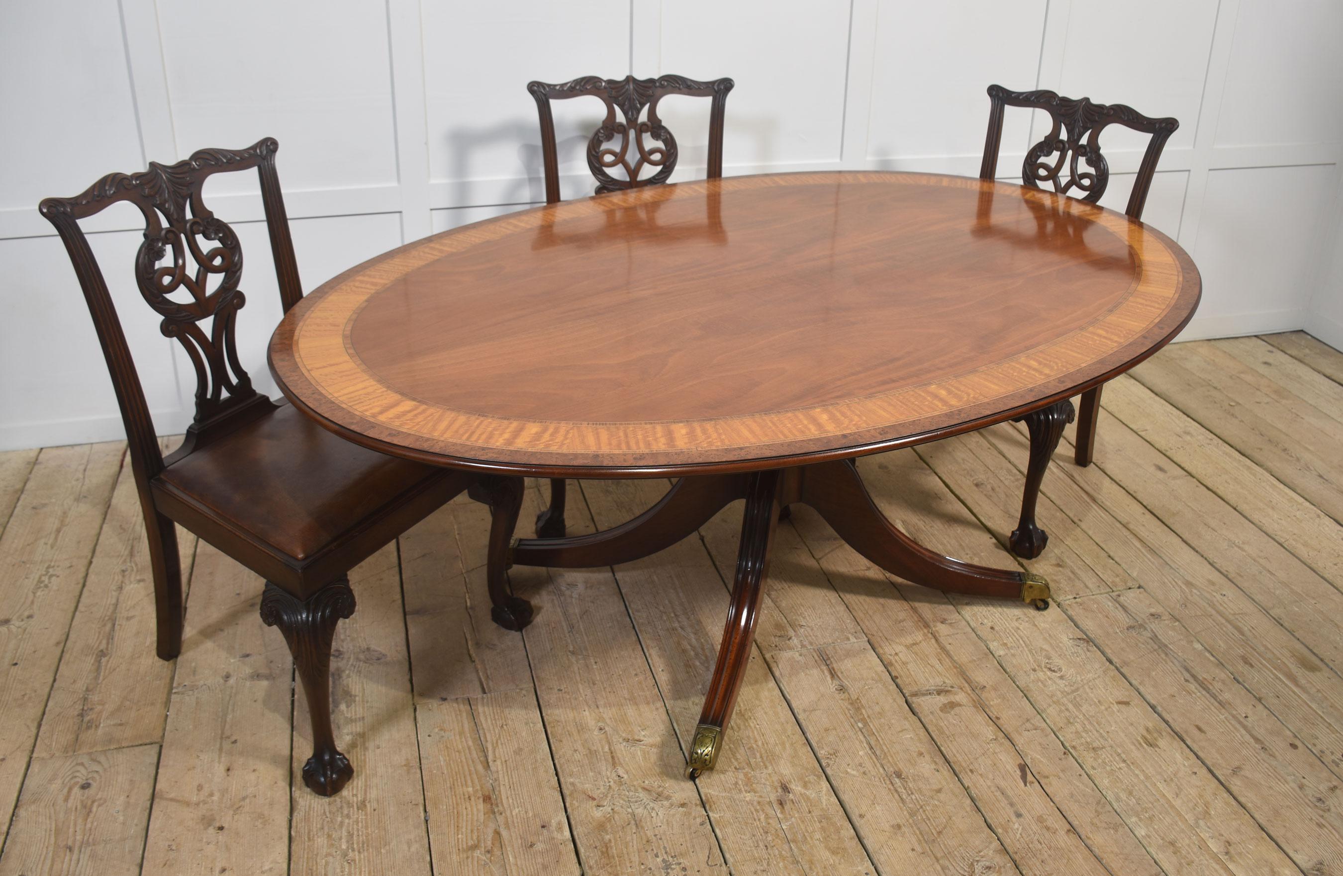 Ein hochwertiger ovaler Mahagoni-Esstisch im Regency-Stil mit einer wunderschön gemaserten Mahagoni-Platte und einer exquisiten Umrandung aus Satinholz und Wurzelnuss mit Querbändern, akzentuiert durch eine feine Saiteneinlage. Die Oberfläche des