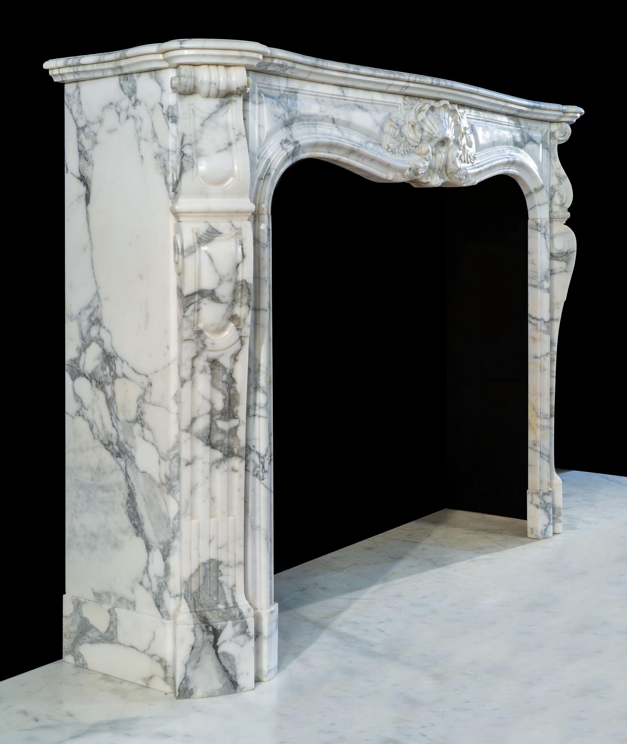 Ein schöner Kamin aus Pavonazzo-Marmor im Rokoko-Stil von Ludwig XV. Das serpentinenförmige Regal sitzt über einem schön geschnitzten, getäfelten Fries, in dessen Mitte eine Muschelkartusche steht, die von Olivensprossen umrahmt wird. Diese wird von