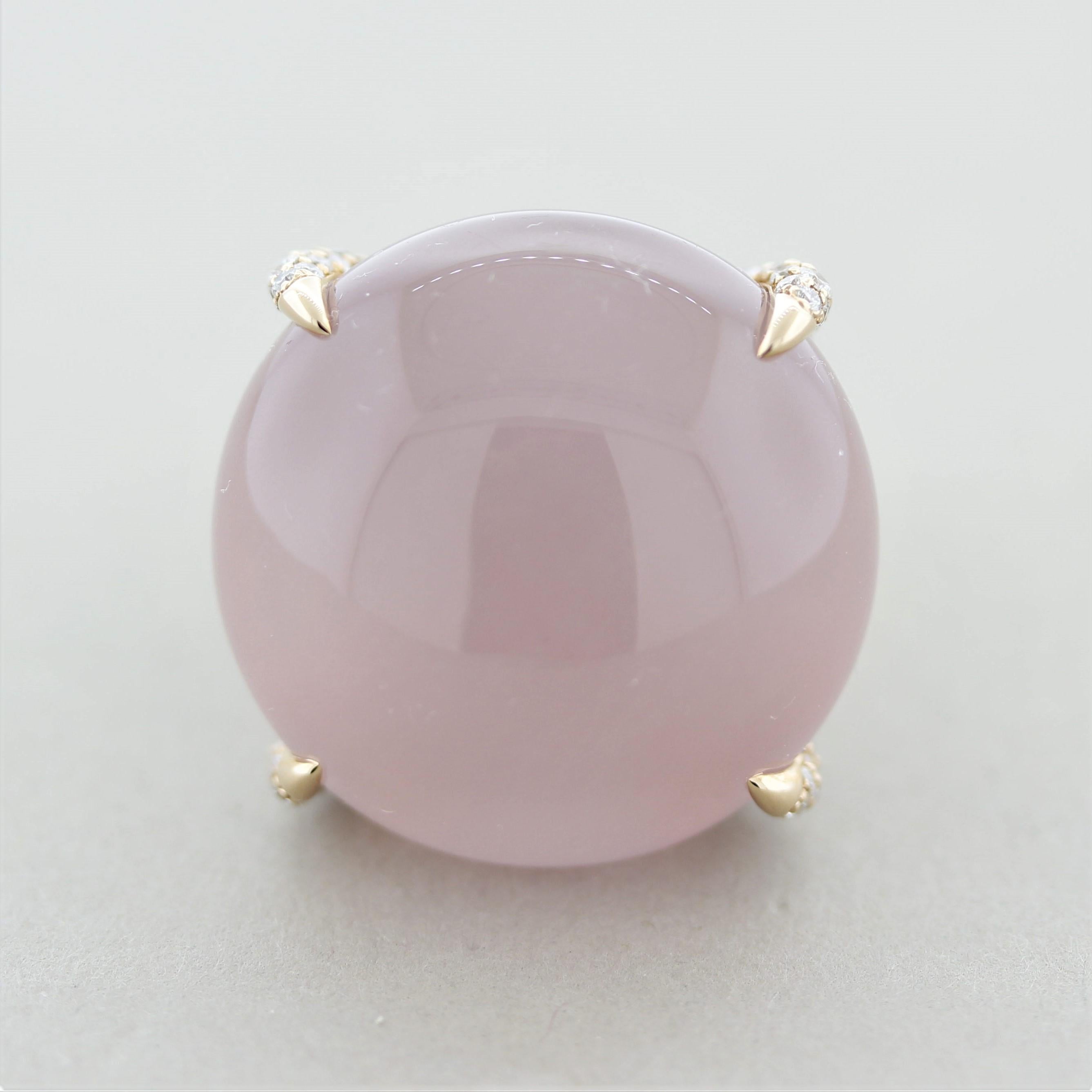 A big, bold, and beautiful cocktail ring featuring a fine cabochon rose quartz weighing 53.70 carats. It has a lively pink color and a smooth polish that brightens the stone. It is set in 4 sleek claw prongs that are set with diamonds on them. The