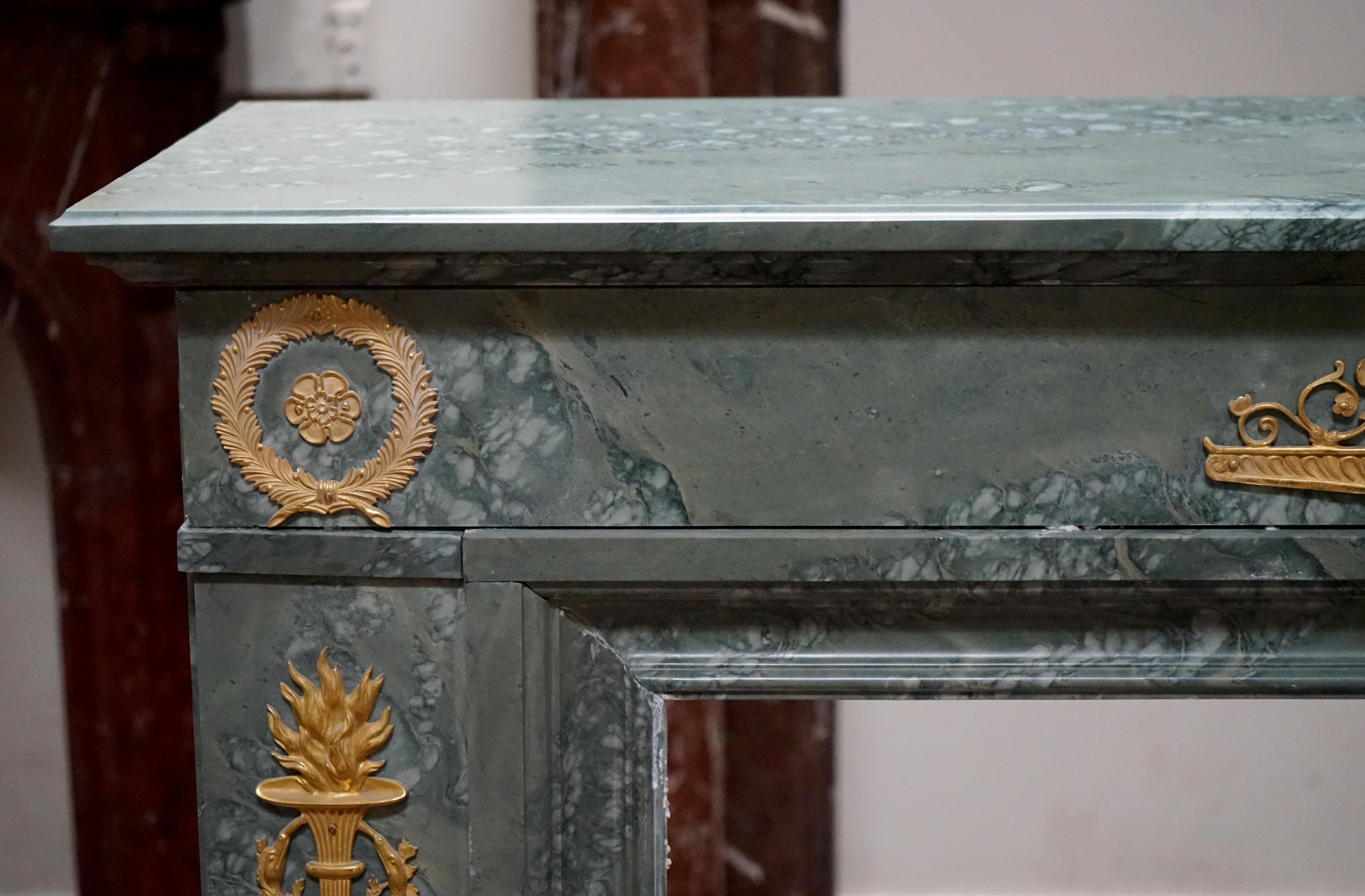 Fine Russian Empire mantel with gilt bronze ormolu fittings. Carved from a rare green-grey marble from Ural Mountains, this mantelpiece features a molded rectangular shelf overhanging a plain lintel fitted with a pair of gilt bronze wreaths in each