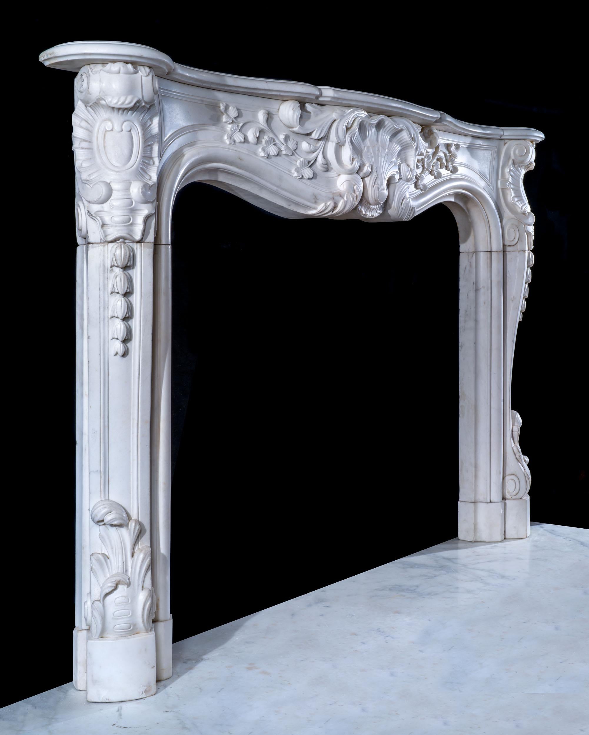 Une belle cheminée écossaise en marbre statuaire rococo. La tablette serpentine moulurée repose sur une frise lambrissée spectaculaire, centrée par un motif de grillage et un décor de feuillage en volutes. Ceci est reflété par les blocs d'enclos à