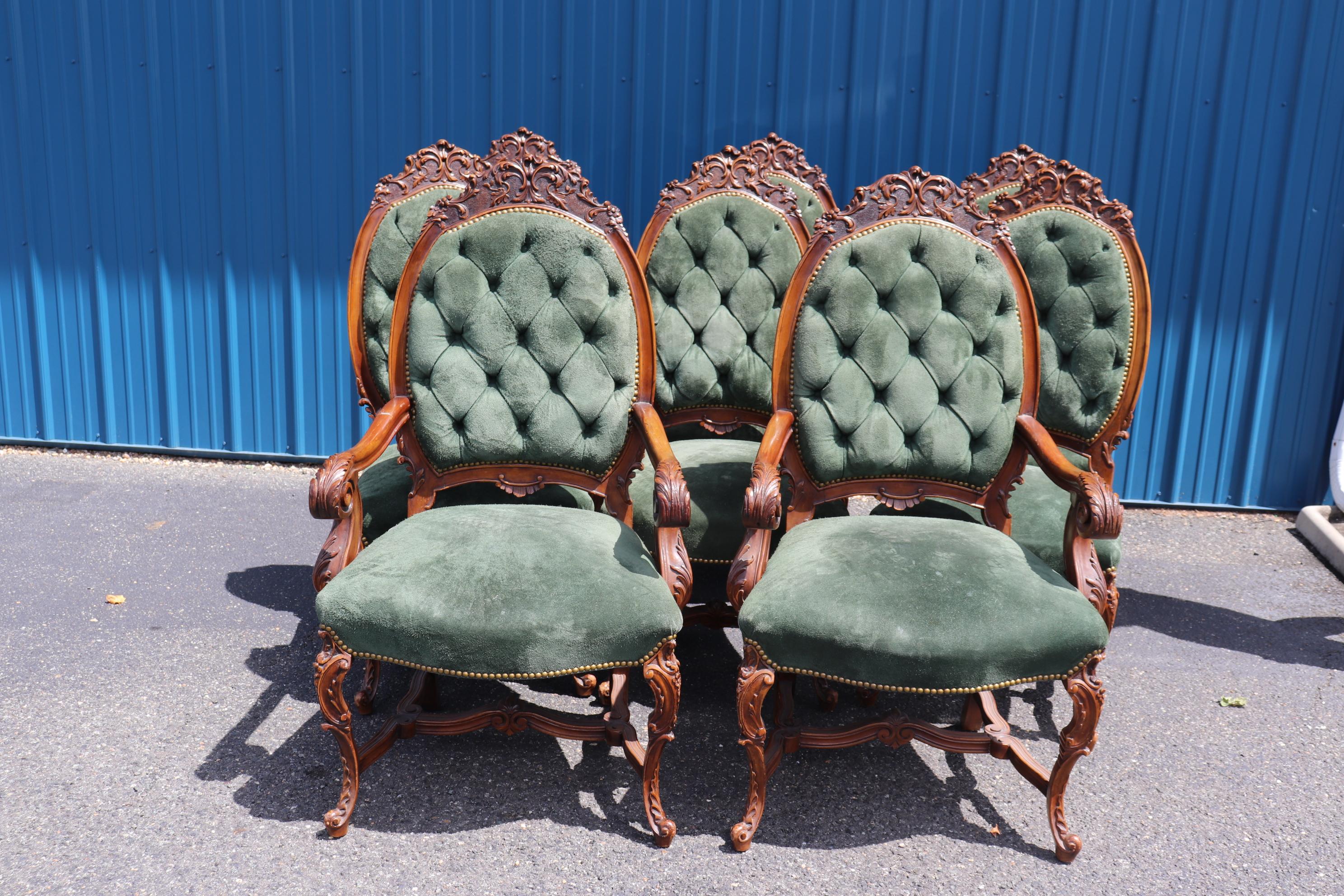 This is a fantastic set of finely carved walnut diing chairs of the late Victorian era. The chairs are spectacularly carved and stippled on their backs and feature genuine green suede leather seating with nailhead trim. The chairs are big, beefy and