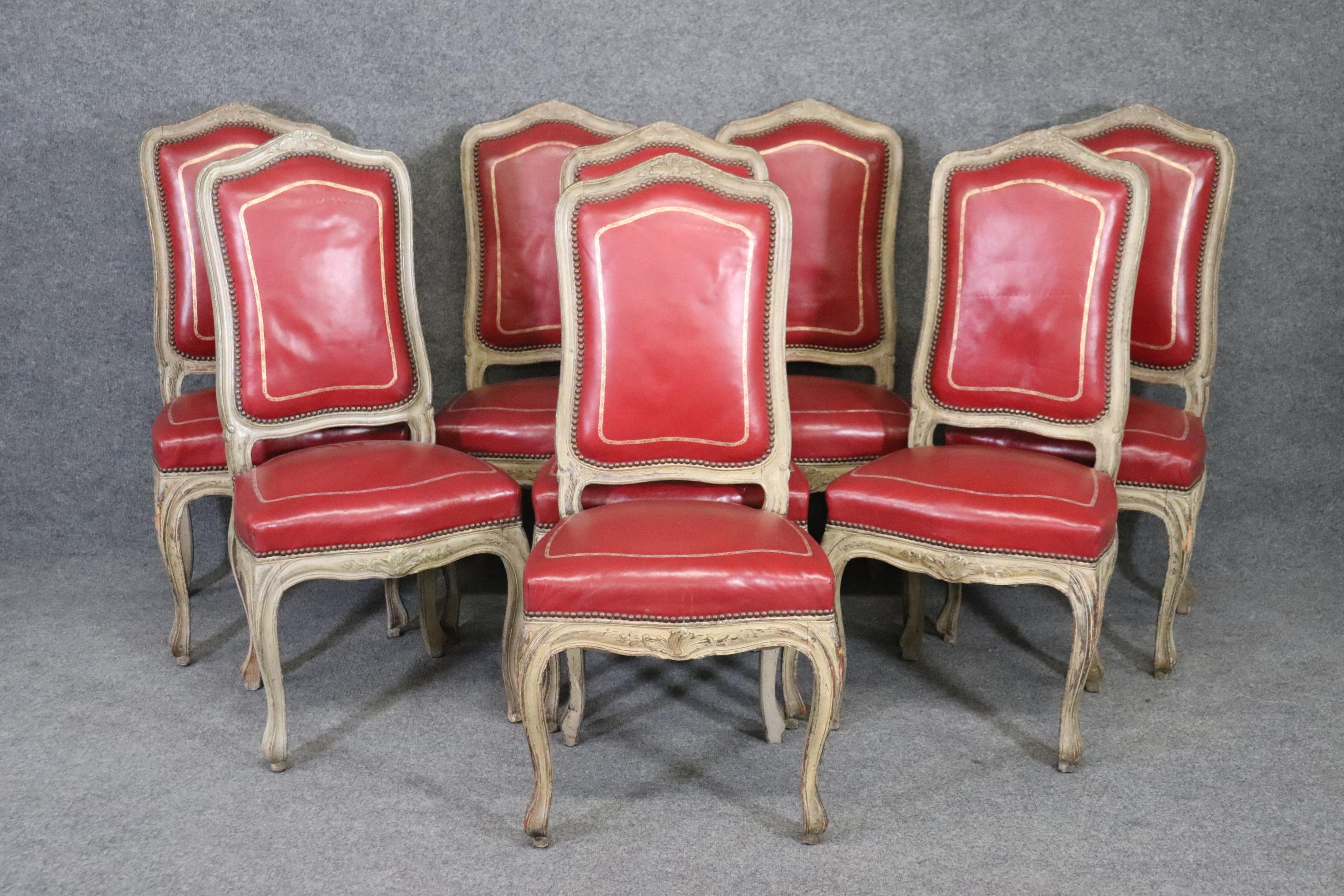 This is a very unique set of 8 French-made 1920-30s era dining chairs in an antiquewhite painted finish with bright lipstick red leather with gold tooled leather. The embossed leather really adds needed opulence to an otherwise more casual look and