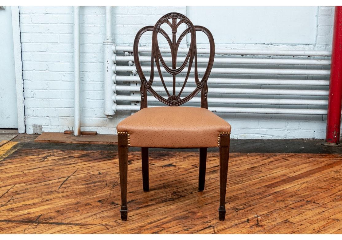 Very well made set of 12 Sheraton style dining chairs, circa 1920s. Including two arm and ten side chairs. The chairs with heart shaped openwork backs with Prince of Wales triple feather crests. Raised on carved square tapering legs with spade feet