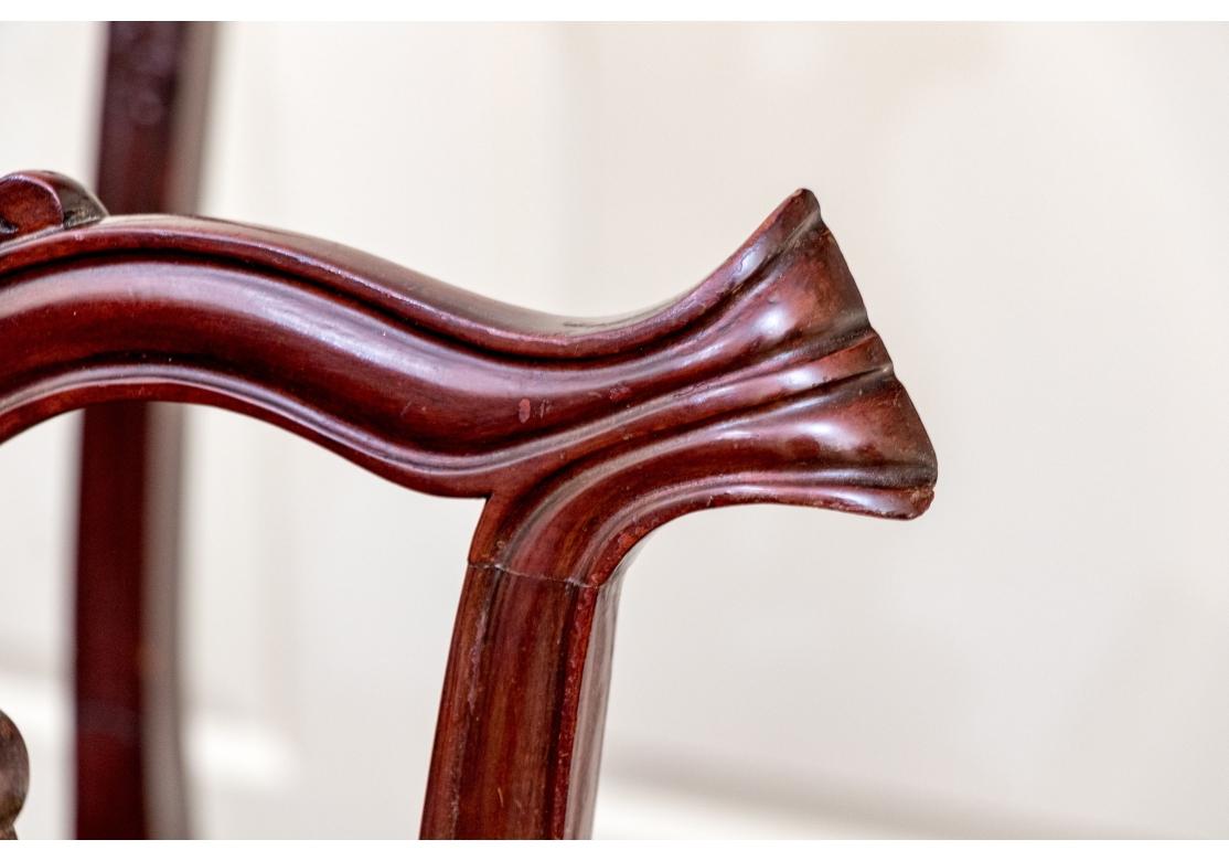 Set di otto sedie in mogano in stile Chippendale composto da 2 poltrone e 6 sedie laterali. Le sedie presentano un'intricata stecca posteriore che si interseca, una seduta in finta pelle, ginocchia pesantemente intagliate, gambe anteriori a cabriola