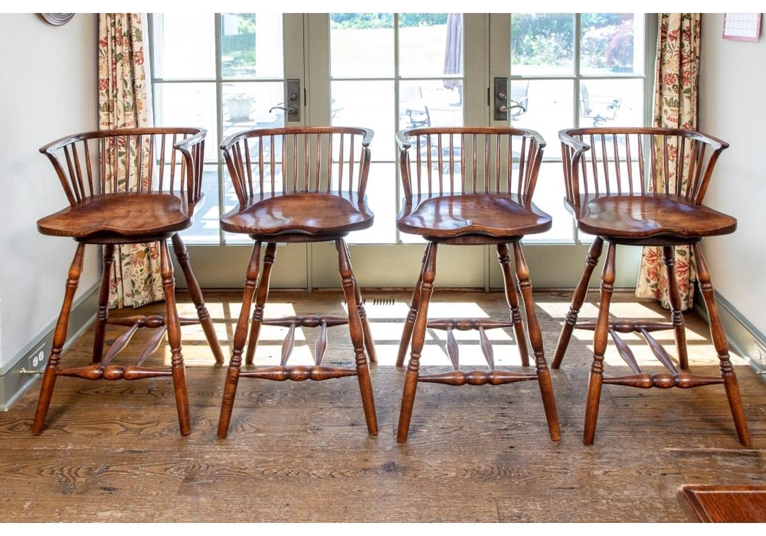A very well-made set of Windsor style bar stools with solid ash seats having a very handsome graining and in a pleasing Chestnut colored stain. The Stools have good weight, strongly turned legs and double H stretchers, comfortable Saddle Seats,