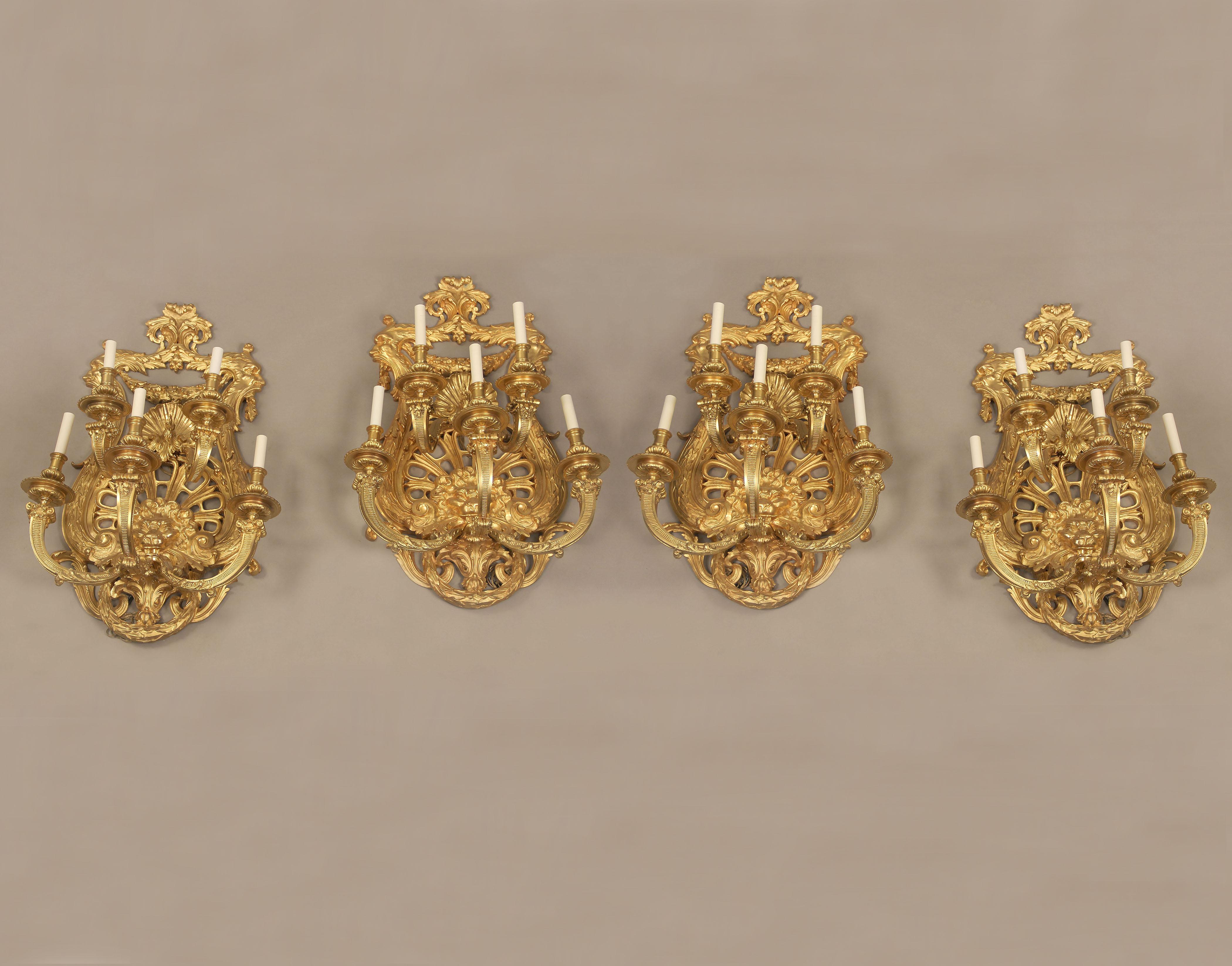 A fine set of four important late 19th century gilt bronze five-light sconces

Heavily chiseled gilt bronze frames decorated with mens faces and a sea shell, centered by a lions mask with five tiered lights.

If you are looking for a chandelier,