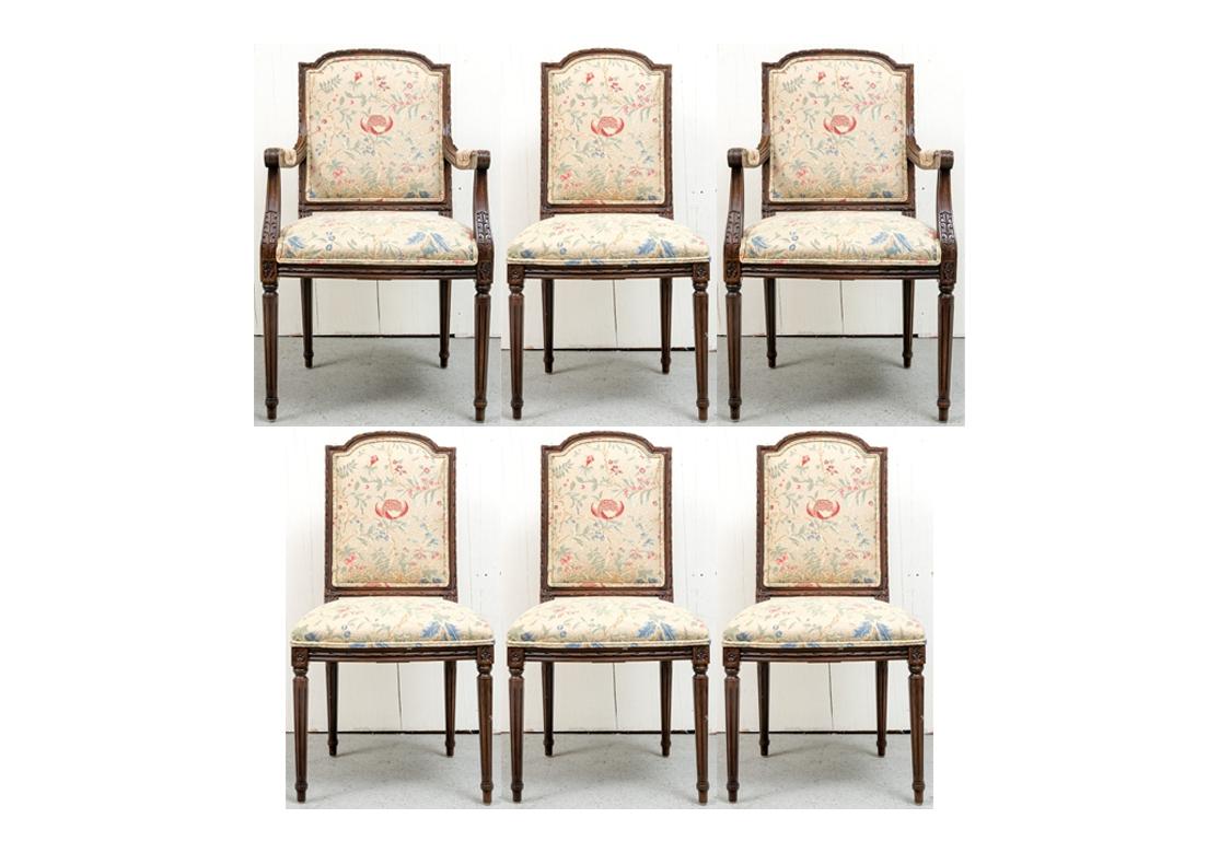 An exceptional set of French Style dining chairs by noted maker E.J. Victor. The frames feature bold carving with stylized Acanthus Leaf motif, fluted and tapering legs, and fine French styling. The fabric is in a very fine Crewel Work type with