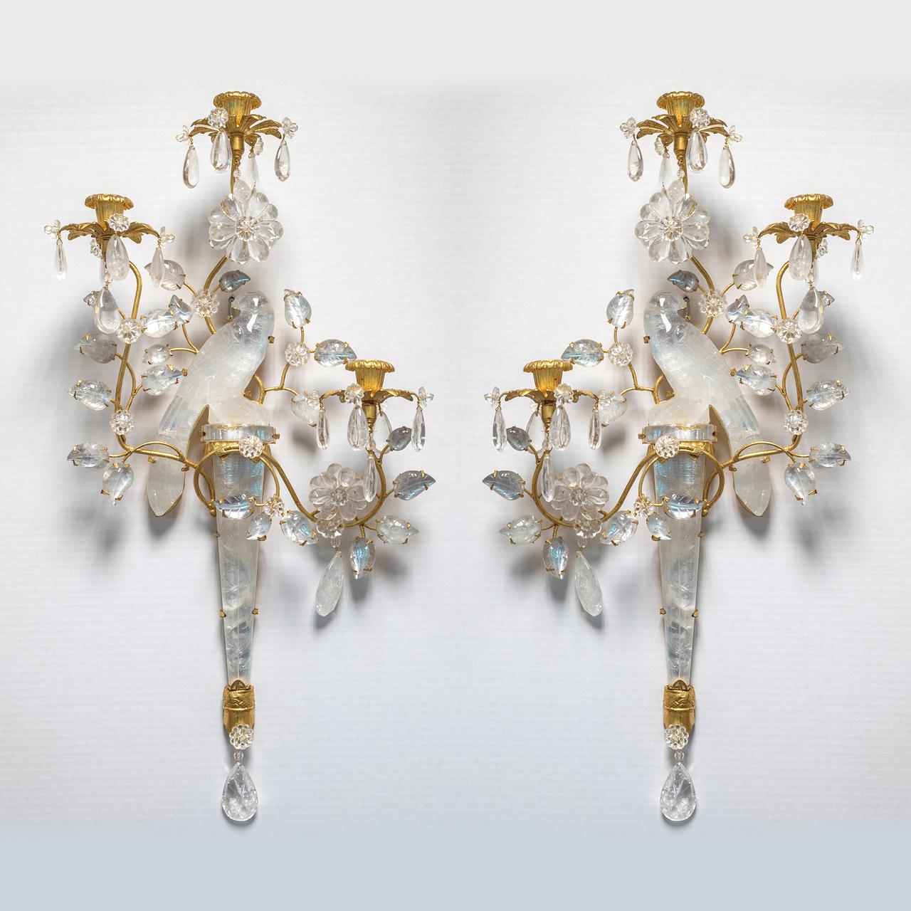Un ensemble exquis de quatre appliques murales de style français Baguès à deux lumières en bronze doré et cristal de roche avec ornementation de perroquets et de feuillages sculptés.

Nouvelle annonce pour une seule paire d'appliques, réalisée après