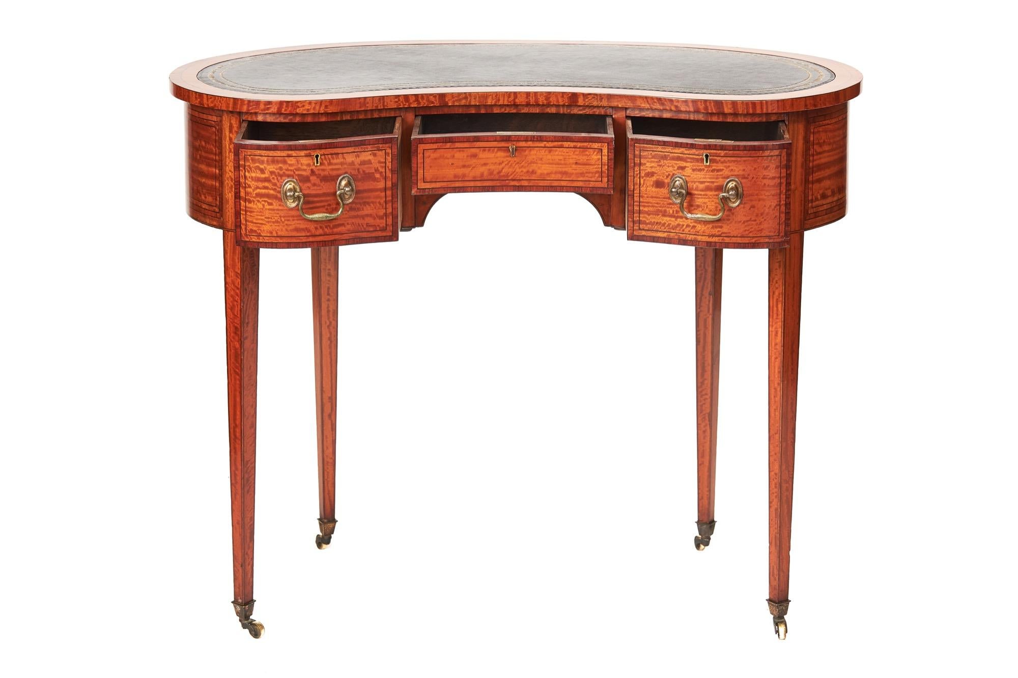Fina mesa de escribir con incrustaciones de madera satinada Sheraton Revival circa 1880s
Parte superior en forma de riñón, con parte superior en cuero negro, con grabado dorado, con
Satinwood y Kingwood Cross banding,
3 cajones en la parte