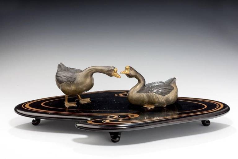 A fine Showa period okimono of two geese on an original black lacquer stand with original box.
