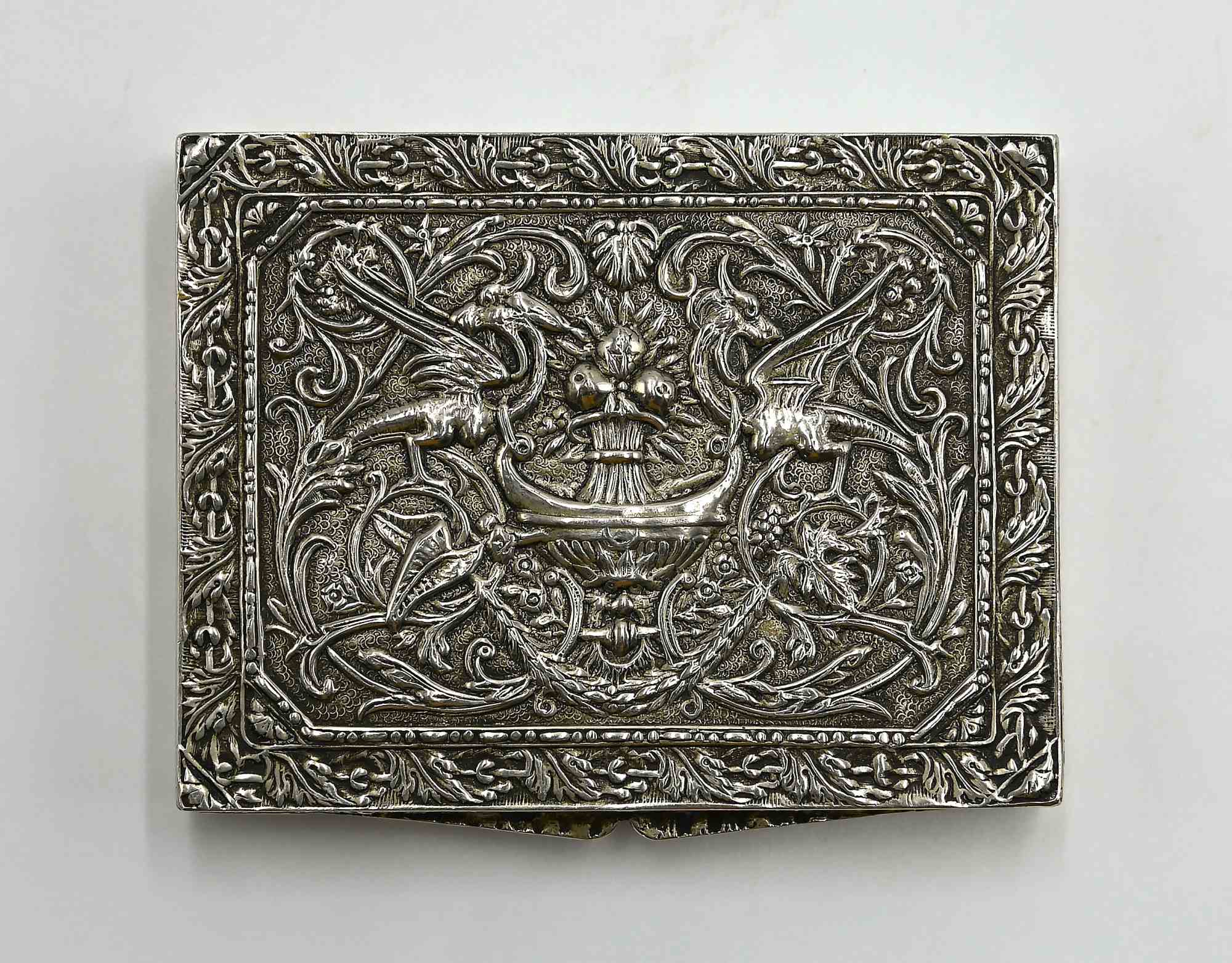 Una superba tabacchiera rettangolare in argento, realizzata con maestria all'inizio del XX secolo, con decorazioni squisitamente cesellate e repoussé. Il coperchio con cerniera è riccamente ornato da un fogliame che incornicia il motivo centrale di