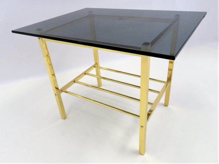 Wonderful Minimalist polished solid brass side table with dark smoked glass top. Tubular brass stretcher shelf. Superior craftsmanship. Cocktail table, end table, nightstand or bedside table.
Measurements:      Glass top 24