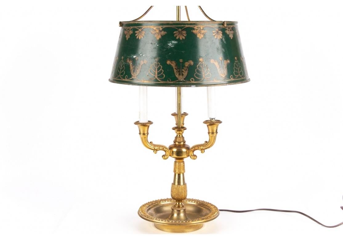 A very fine table lamp with traditional form, handsome well-crafted brass-work, green painted metal shade and well-crafted arrow finial. Very good condition with expected time-borne age and wear, the lamp presenting very well. 
The Bouilotte lamp