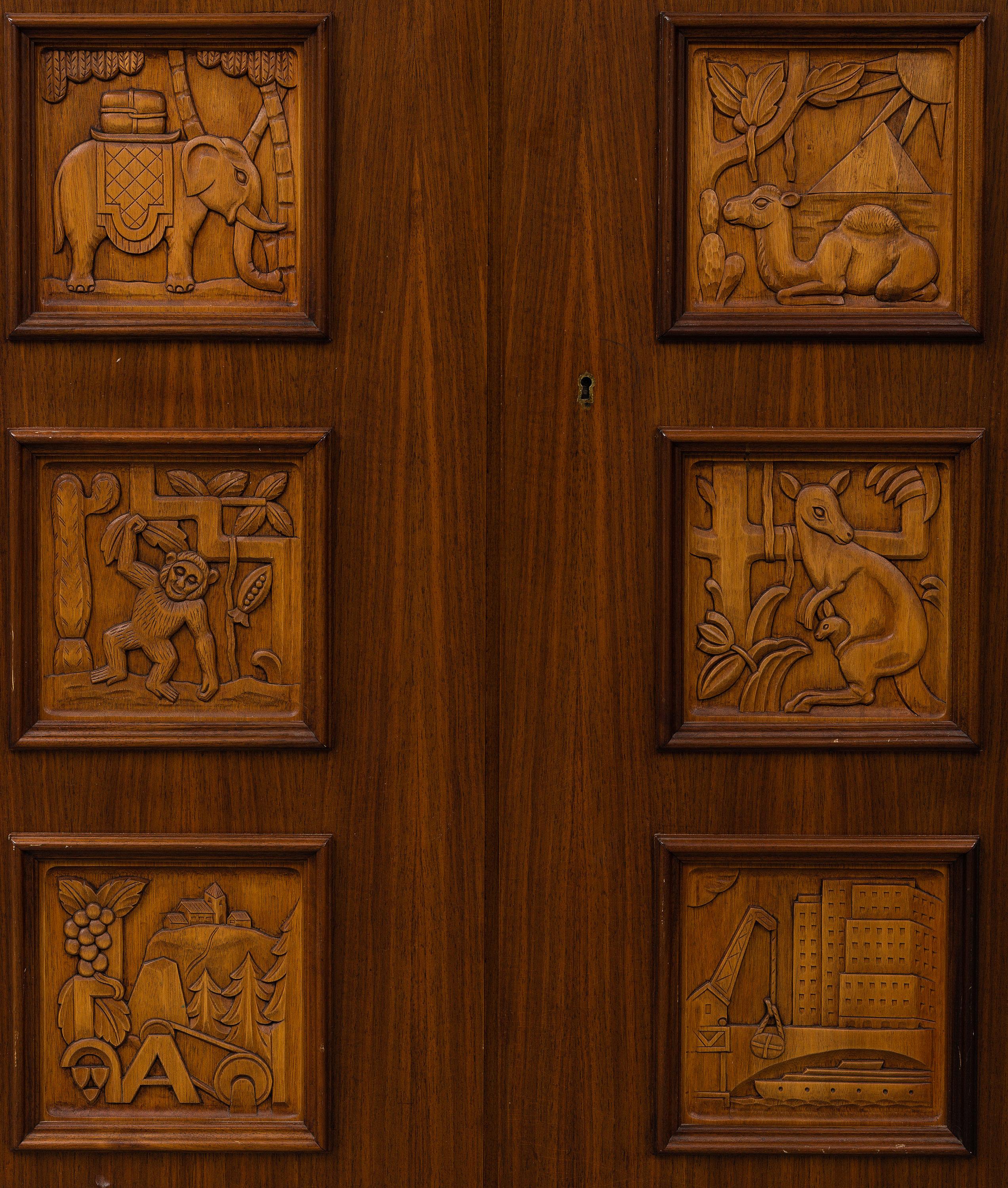 Fine 2-door cabinet by Swedish designer Eugen Hoglund, with 6 hand carved panels depicting
various animals and landscapes in fruitwood and beech, The cabinet has two interior shelves and two
stationery pull out drawers. The shelves are