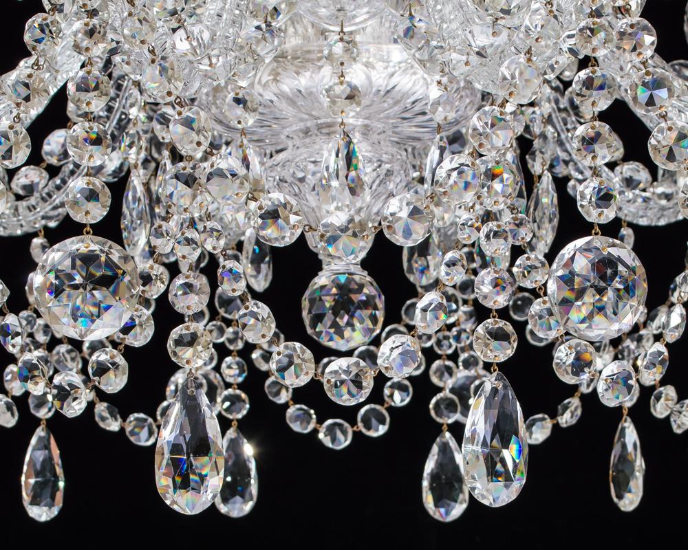 A fine cut glass chandelier with multi baluster stem, the main receiver bowl cut with large drop hung scallops issuing ten thumb cut scroll S-arms supporting flat diamond and scalloped drip pans and candle nozzles, the upper section of the