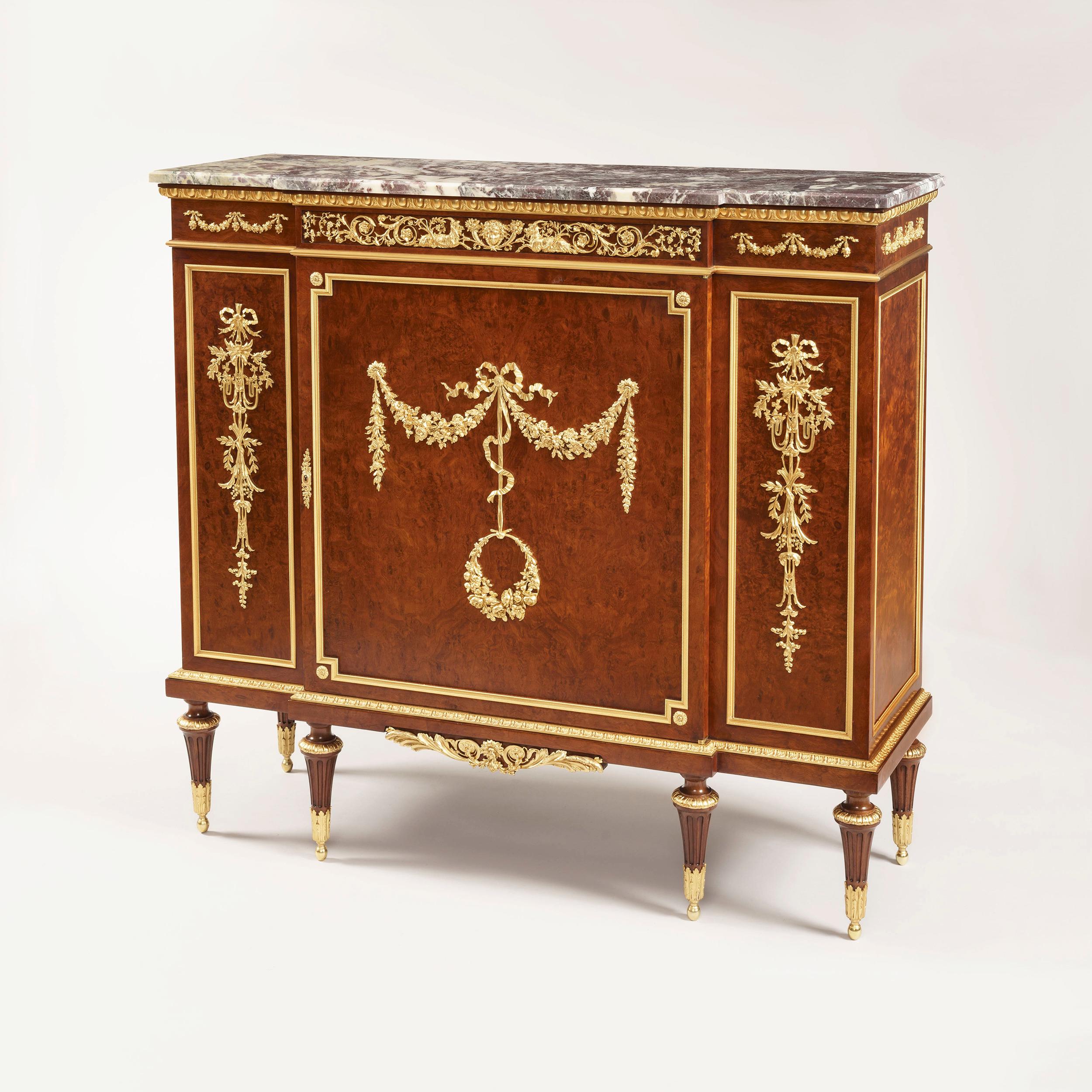 A fine side cabinet by François Linke

In the Louis XVI manner, of gentle breakfronted form, constructed in thuya, and adorned with bronze doré mounts of the finest quality; rising from turned and tapering cannelure and leaf cast ormolu clasps,