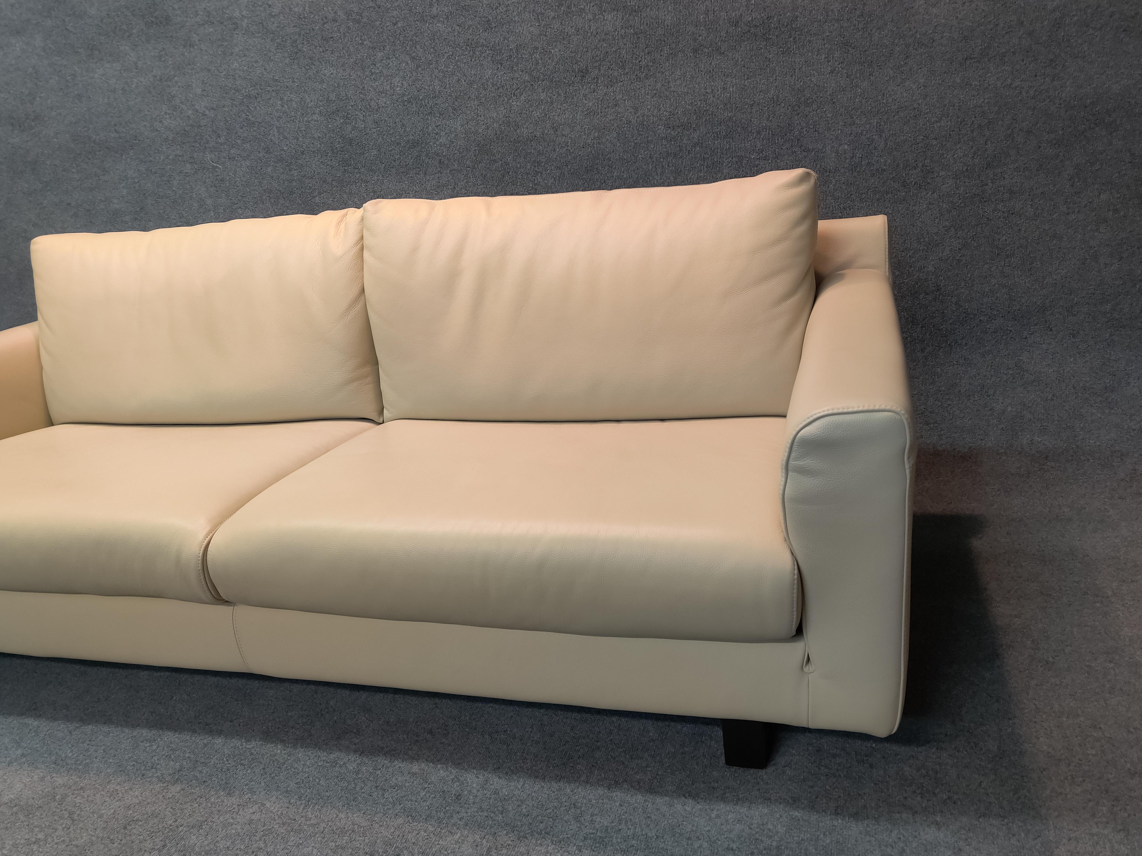 A superb and classy sofa designed and manufactured by Nicoletti of Italy. This sofa is upholstered in off-white top-grain leather on dark wood legs. It has perfect proportions, which are enhanced by the finely tailored and precisely stitched