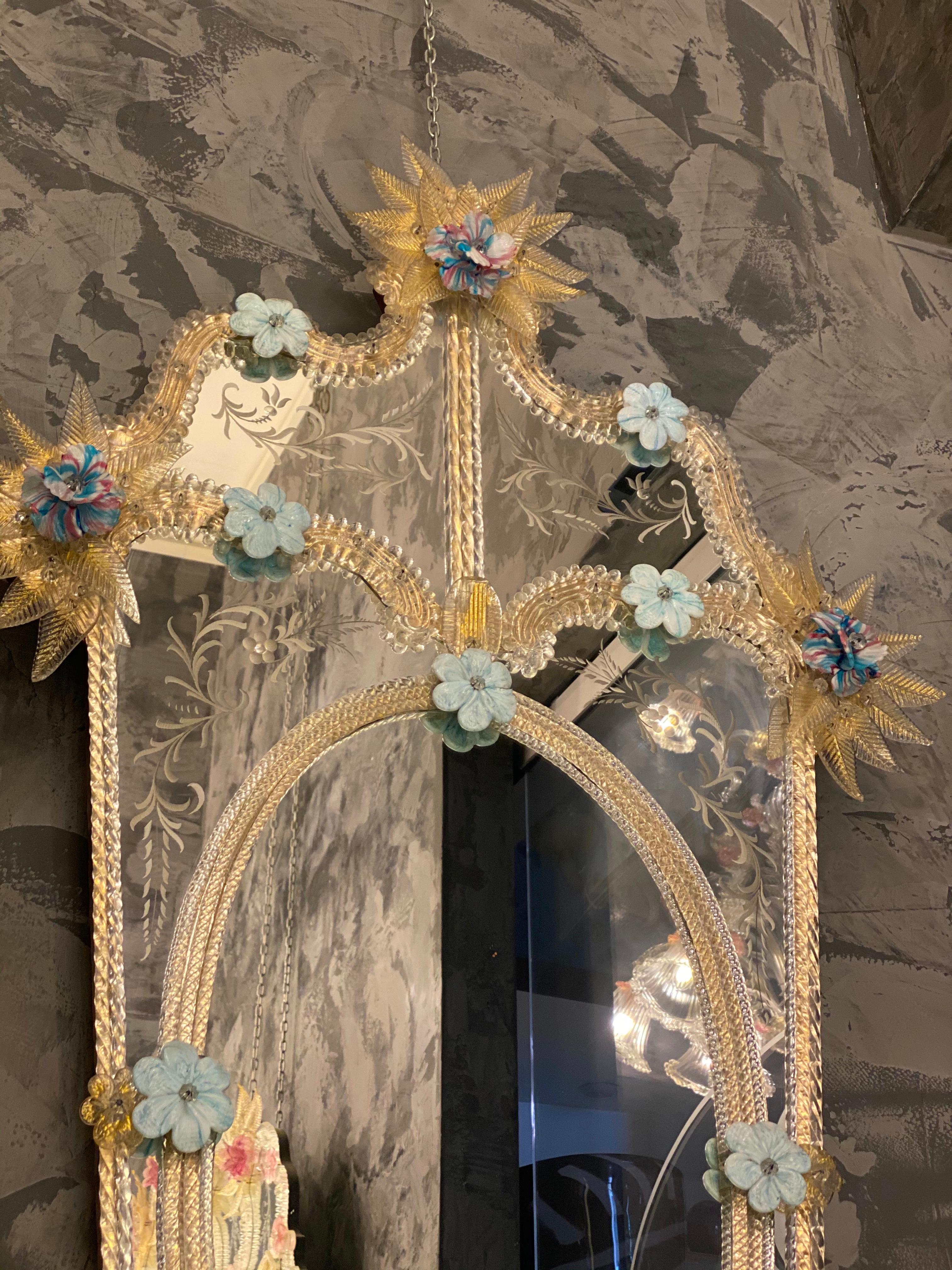 This delicious Venetian mirror features etched figure motifs adorning the mirrored frame. Along the edges of the frame are gold glass rope accents and numerous glass light blu and multicolor pasta vitrea flowers.
Executed by the great a Master of