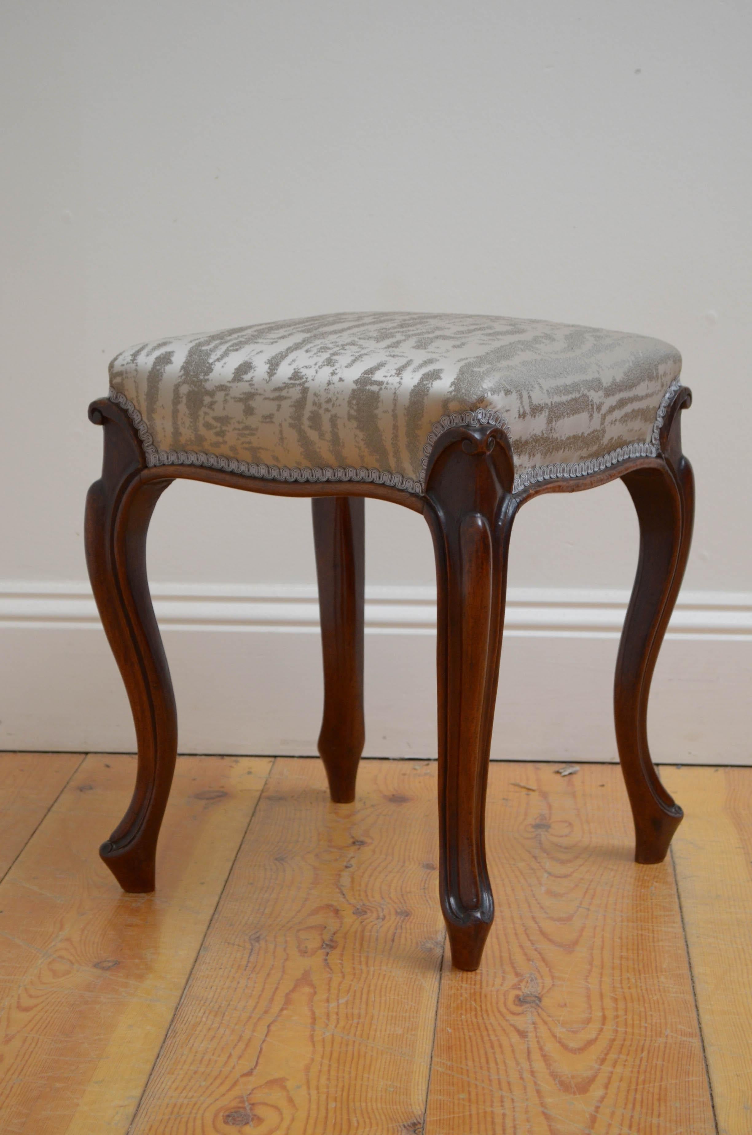 Fine Victorian dressing table stool in mahogany, having newly upholstered seat with silver top cover and four carved cabriole legs united by serpentine moulding. This antique stool retains its original finish which has been revived and waxed,