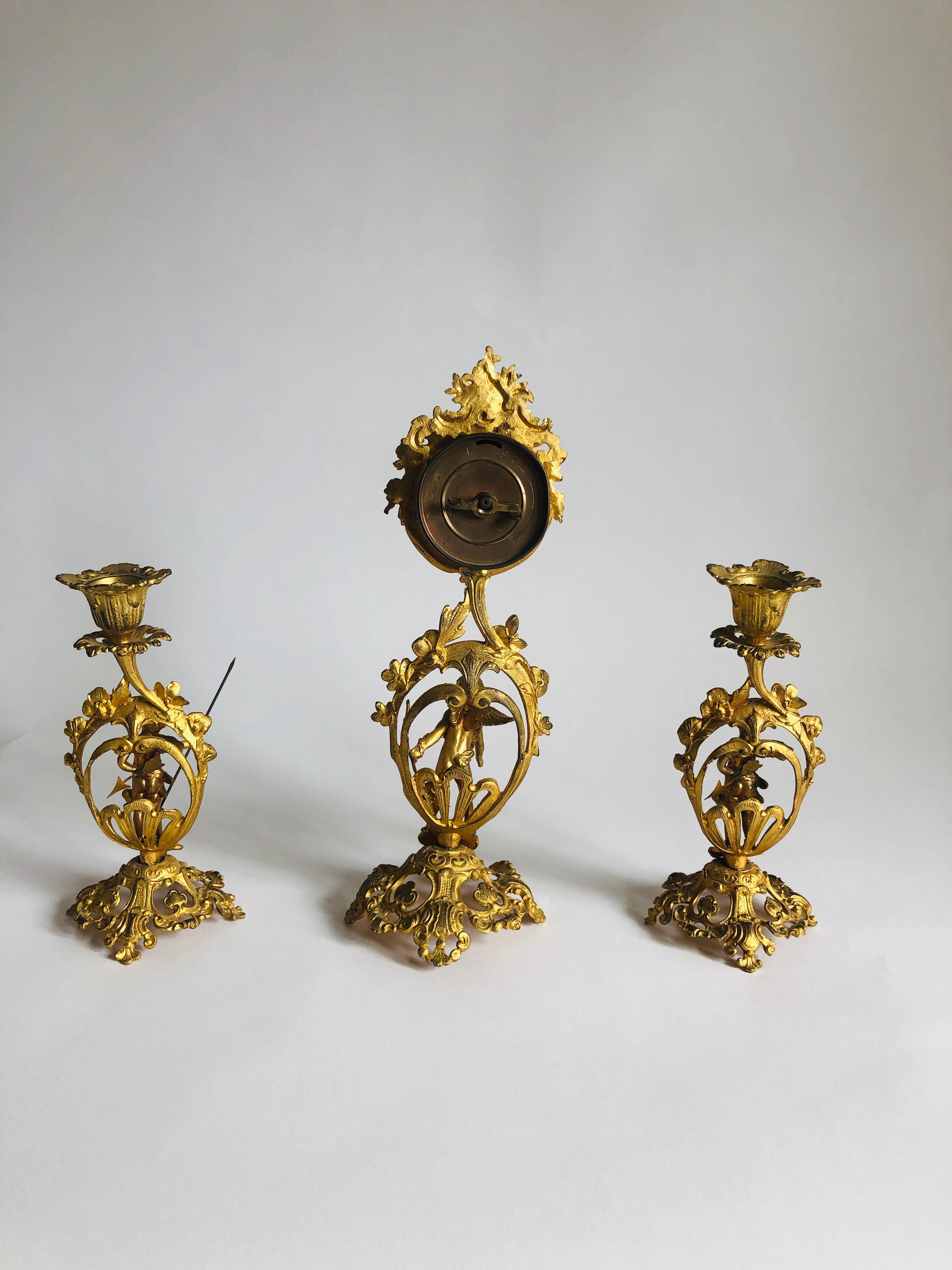 Fine Victorian ornate gilded clock set with delightful ornate cupids and flowers. The clock is an 8 day movement with original hands and a cupid to the base. The candlesticks have attractive shaped tops raised by cupids on an ornate