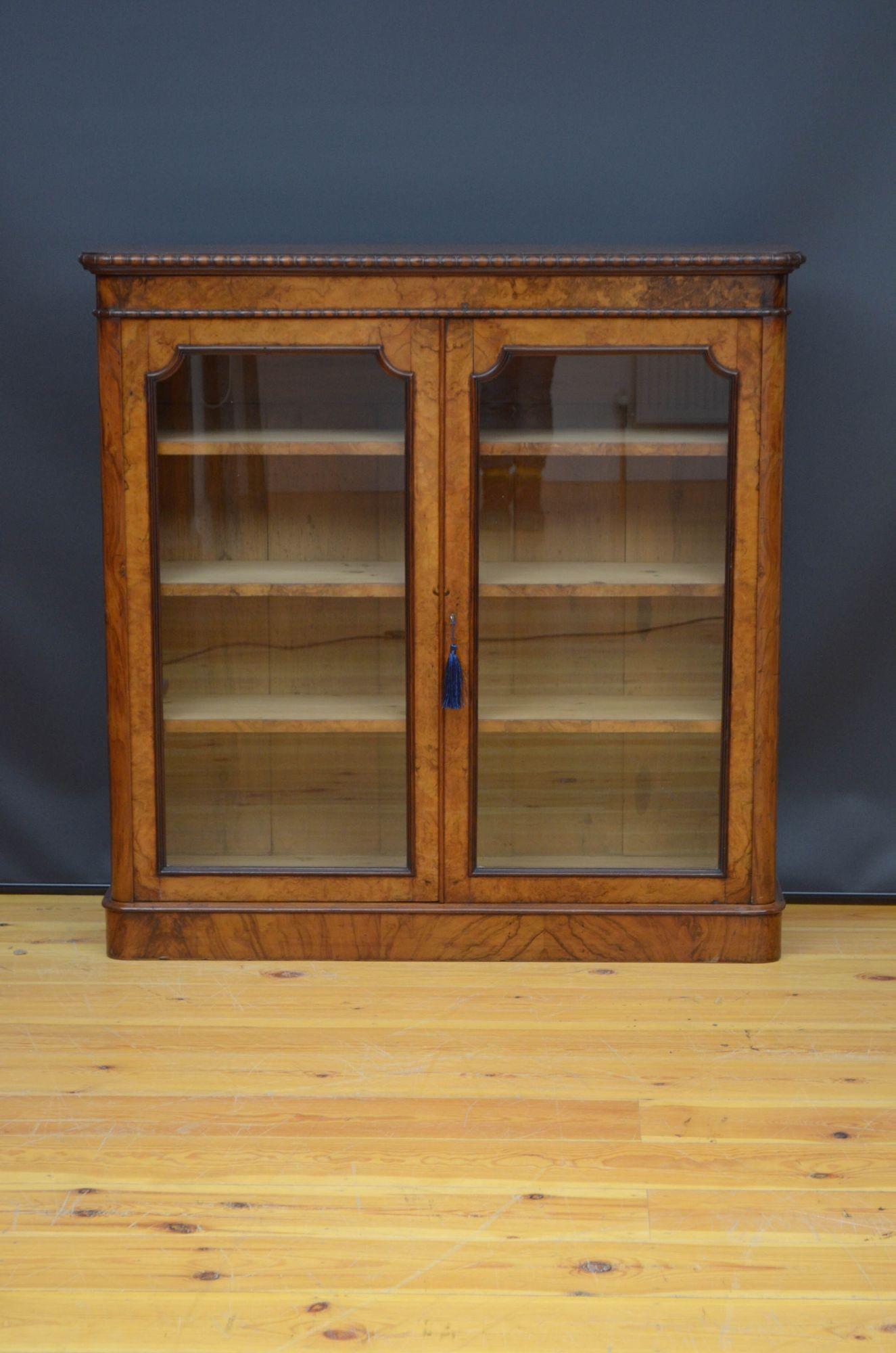 Sn5339 Fine Victorian glazed bookcase, having figured walnut top with carved edge above a pair of glazed doors fitted with original working lock and a key and enclosing three height adjustable shelves, all flanked by rounded corners, all standing on