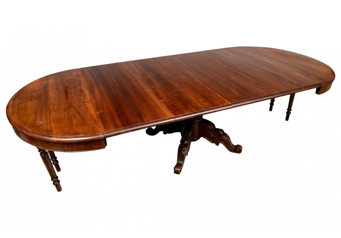 Ca. 1860. A particularly notable Period Victorian Table with the capacity to seat 8-10 when the leaves are utilized. Nearly circular when closed and raised on a strong and  elaborately carved scrolled pedestal base with fruit motifs. Expandable with