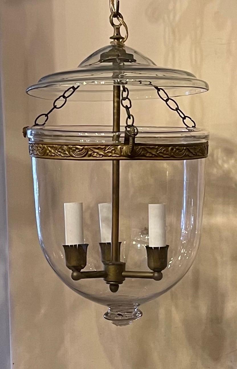 A fine vintage pair of clear glass bell jar lanterns with bronze 3-light clusters in the manner of Vaughan, the fixtures have been rewired and come with chain and canopy as well as mounting hardware.