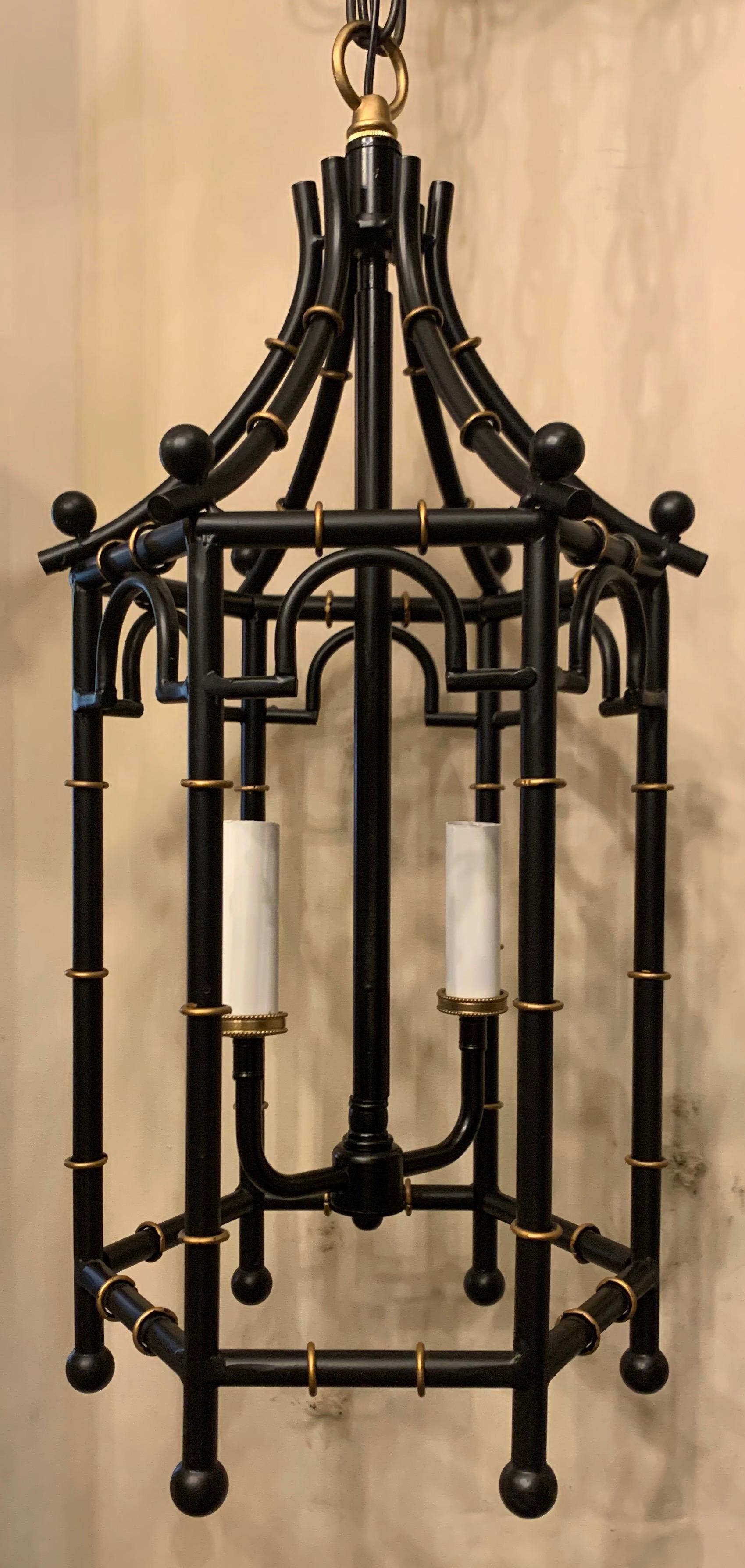 A wonderful vintage pair of black and gold gilt pagoda / bamboo chinoiserie 2-light lantern light fixtures in the manner of Maison Jansen, both fixtures have been completely rewired and are accompanied by chain canopy and mounting hardware.