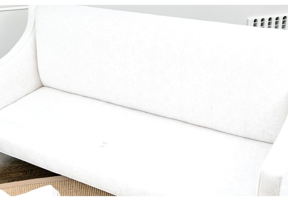Ligero y muy bien hecho Sofá de dos cojines con brazo suavemente inclinado y patas cónicas de madera. Sensación de solidez y comodidad con el cojín del asiento envuelto en pluma de felpa. La refinada tapicería personalizada blanco sobre blanco