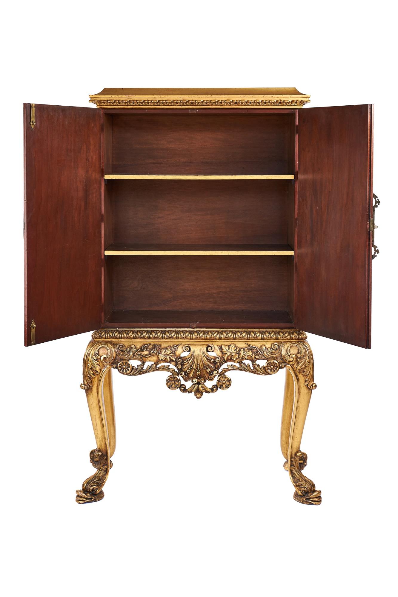 Fino armario de 2 puertas de nogal y dorado sobre peana de la década de 1920,
Parcela dorada y cornisa tallada decorada,
Armario superior de 2 puertas de nogal. con bandas transversales de kingwood, placa de cierre y bisagras de latón fundido fino,