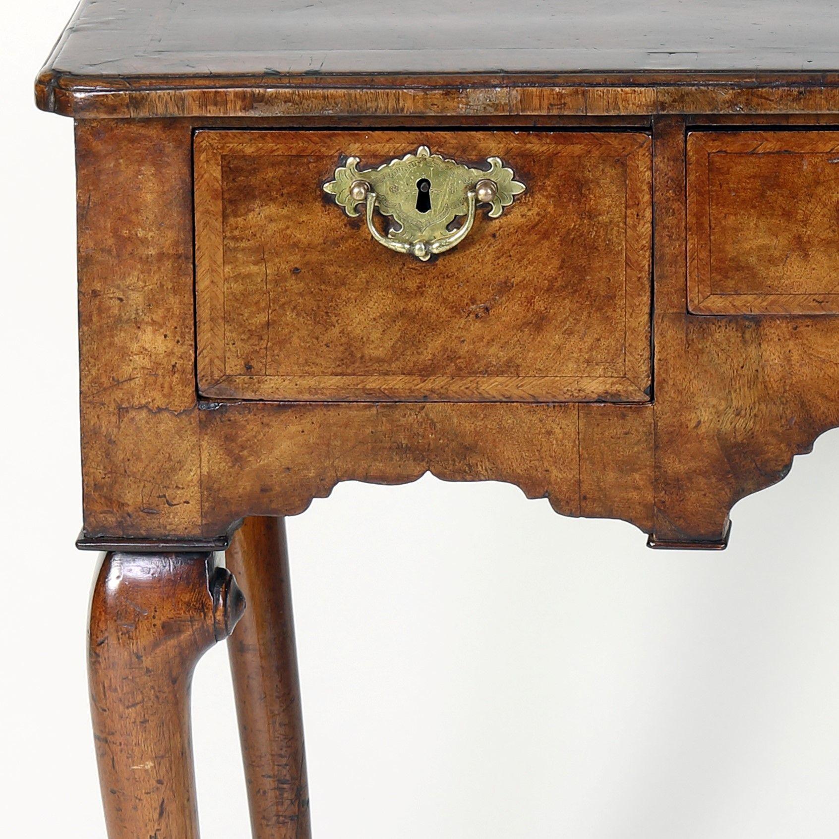 A fine quality George I period Walnut lowboy of wonderful colour and rich patination with cross-banded and herringbone inlaid quartered top having re-entrant corners all round, above an arrangement of three drawers, similarly decorated, and a shaped