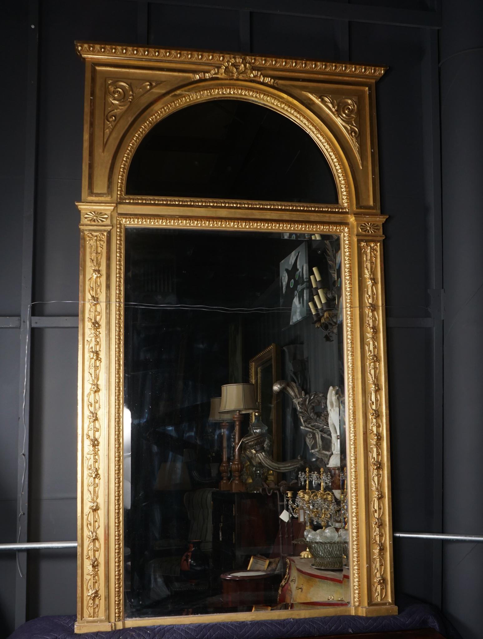 This large and impressive mirror completely water gilded in the matte and burnish technique was made in France circa 1870. The divided bevelled edge plate is the same top and bottom and is surrounded by a well-carved acanthus border. The side carved