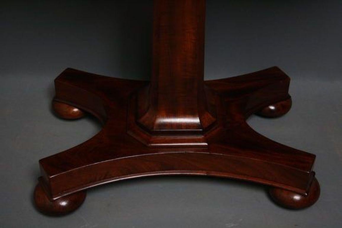 Sn586 Elegant, William IV period, mahogany fold over card table, having figure mahogany top opening to reveal baize interior with shaped frieze having decorative carvings, stands on slim tapering flat facetted column with quatrefoil platform base